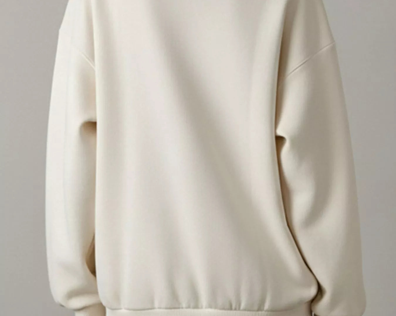 NEWYORKLISTED STYLE COLLECTION: Person wearing a cream-colored sweatshirt against a plain background