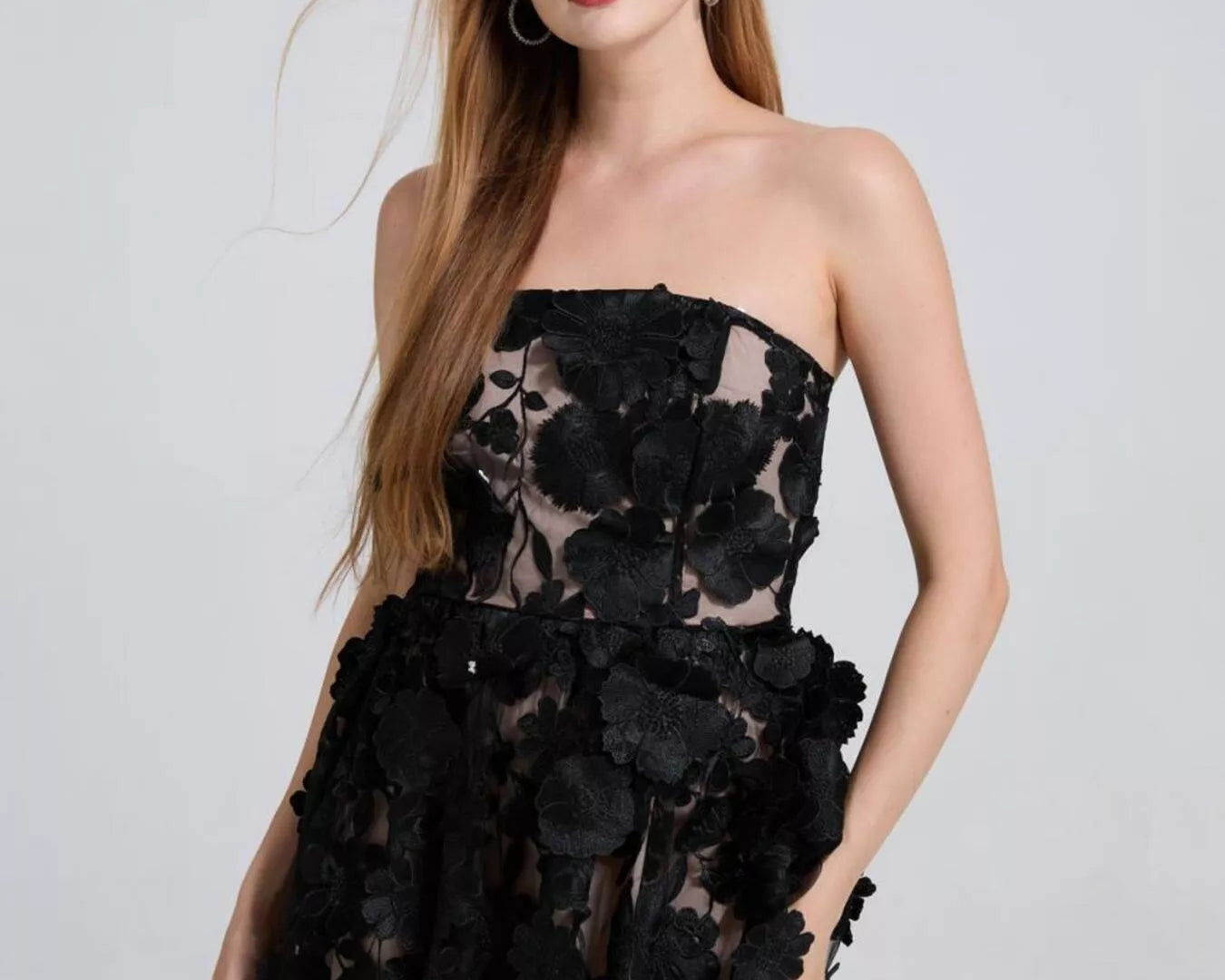 NEWYORKLISTED STYLE COLLECTION: Woman wearing a black strapless dress with floral details on a white background