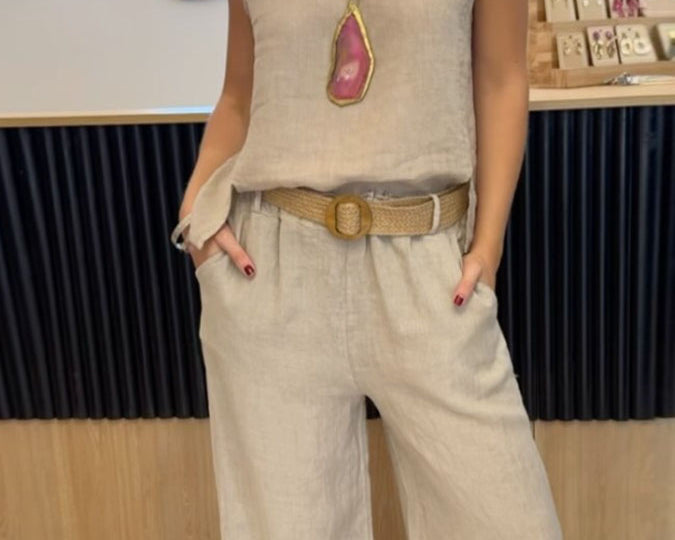 NEWYORKLISTED COMFORT COLLECTION: Person wearing a beige sleeveless top and pants with a belt, standing indoors.