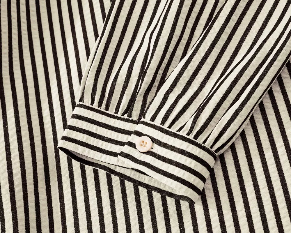 NEWYORKLISTED STYLE COLLECTION: Close-up of a black and white striped shirt with a button detail.