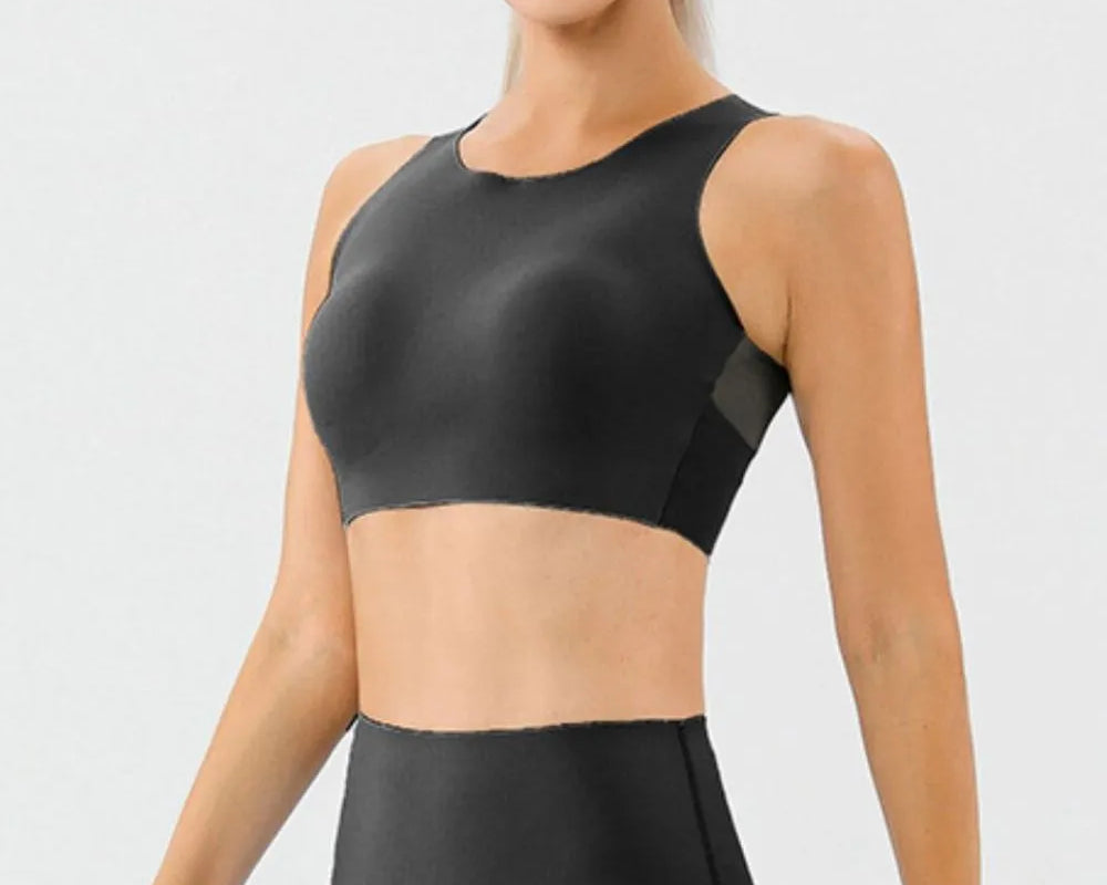 NEWYORKLISTED ACTIVEWEAR COLLECTION: Woman wearing a black athletic top and leggings on a light gray background