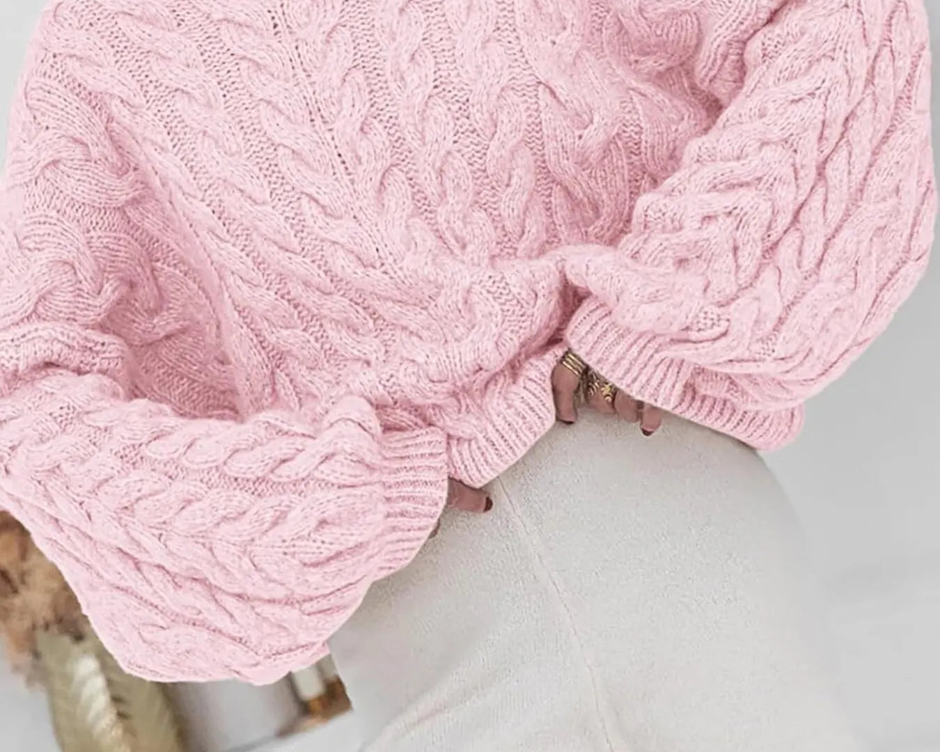NEWYORKLISTED: Person wearing a pink cable knit sweater with a blurred background