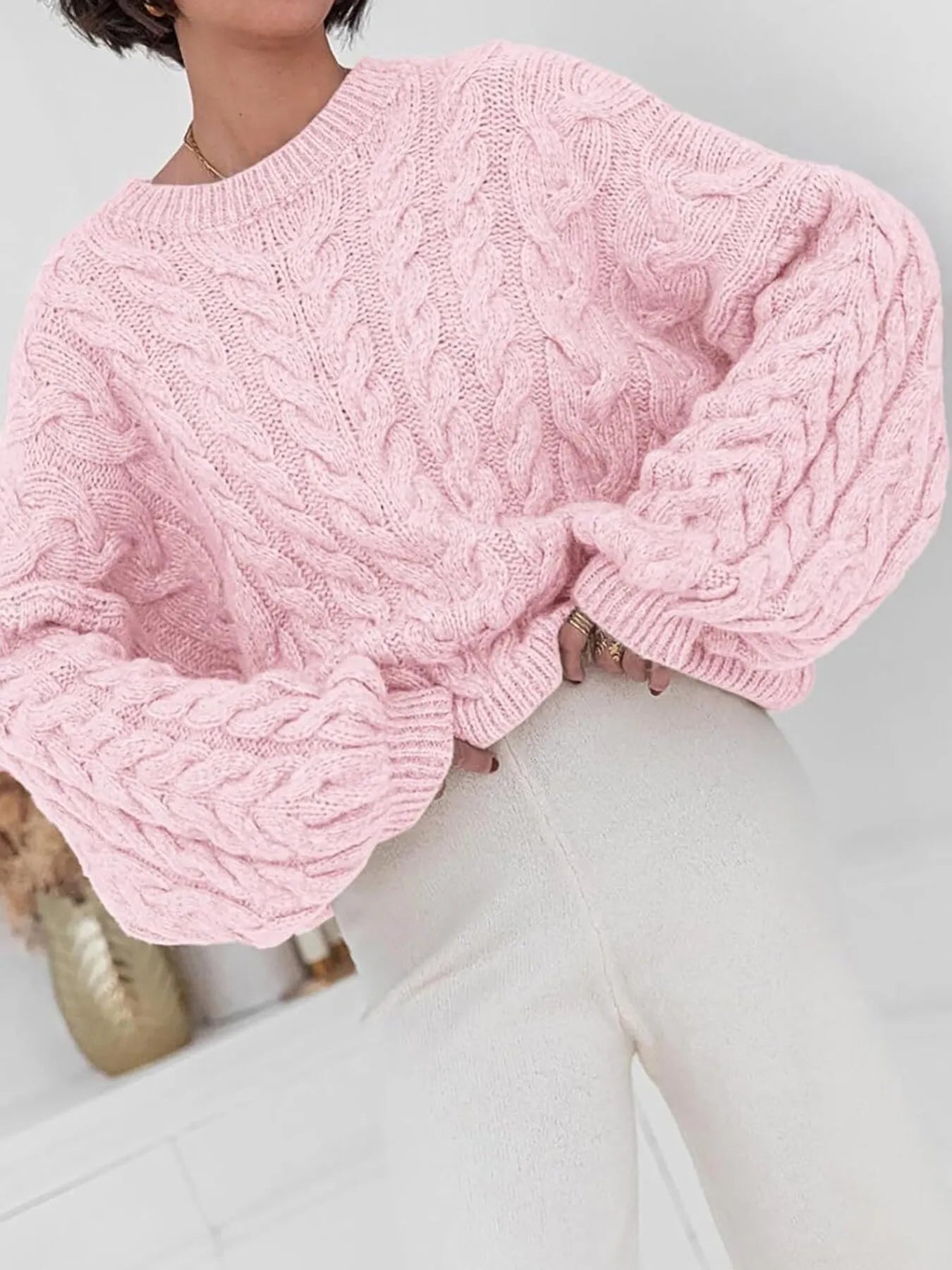 NEWYORKLISTED: Person wearing a pink cable knit sweater with a blurred background