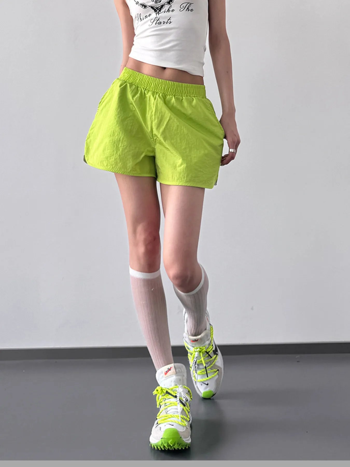 NEWYORKLISTED ACTIVEWEAR: Person wearing bright green shorts and shoes on a plain background