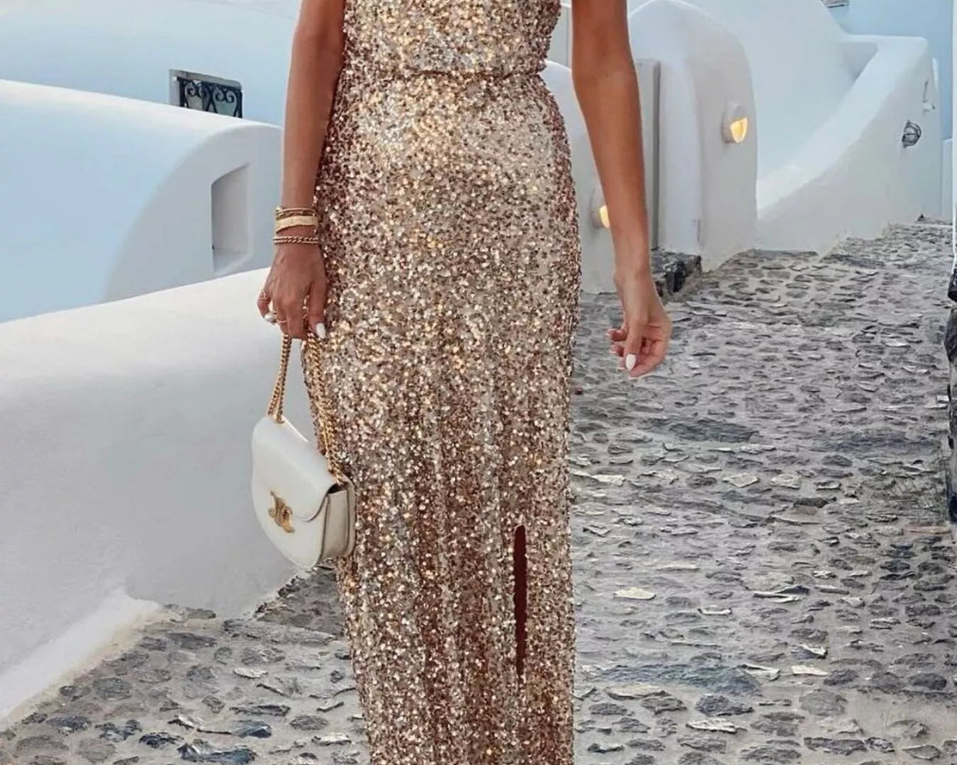 NEWYORKLISTED STYLE COLLECTION: Sequin One-Shoulder Slit Maxi Dress, models wearing a one-shoulder dress standing on a stone path with white buildings and umbrellas in the background.