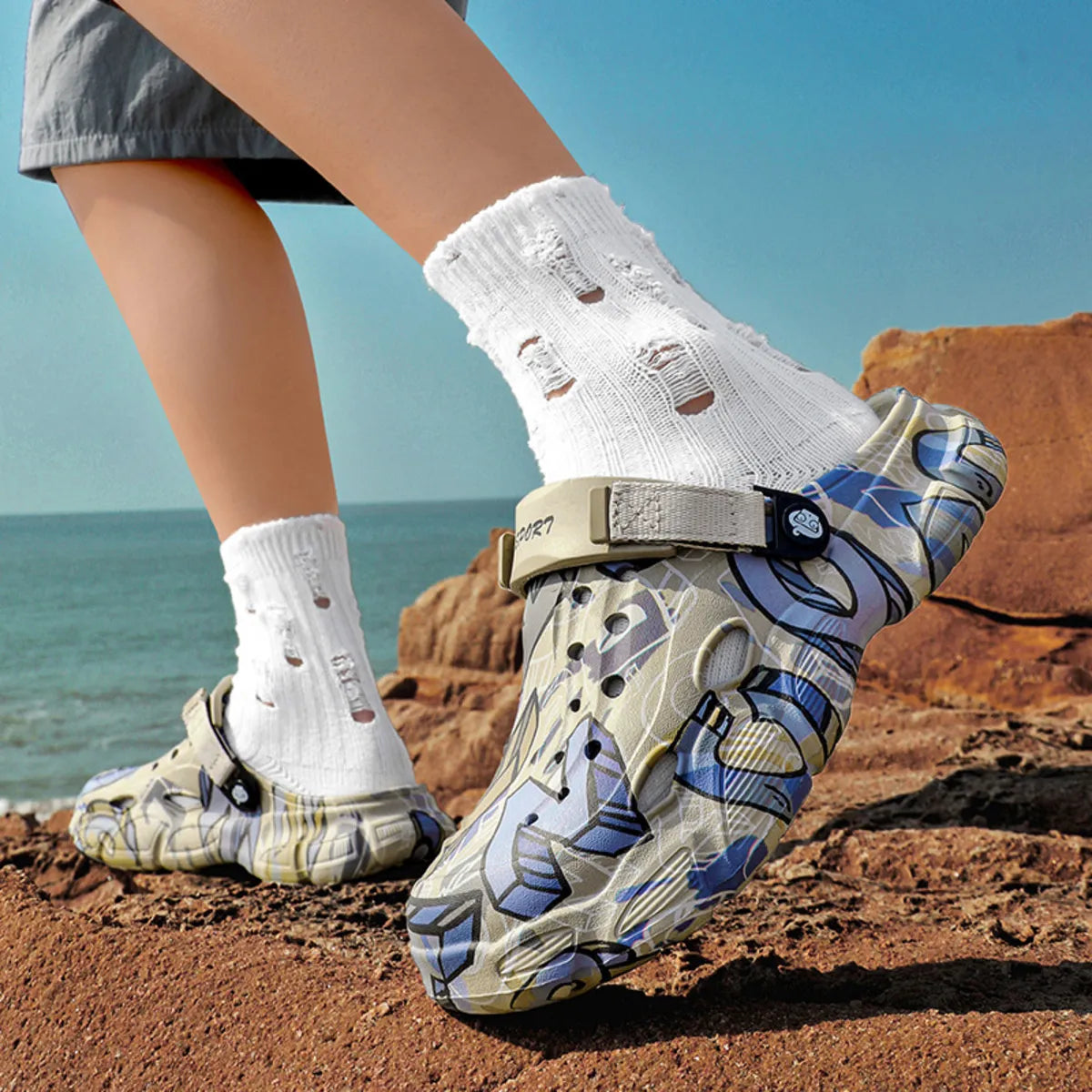 NEWYORKLISTED ATLAS MEN'S COLLECTION: Person wearing patterned shoes and white socks on a rocky beach.
