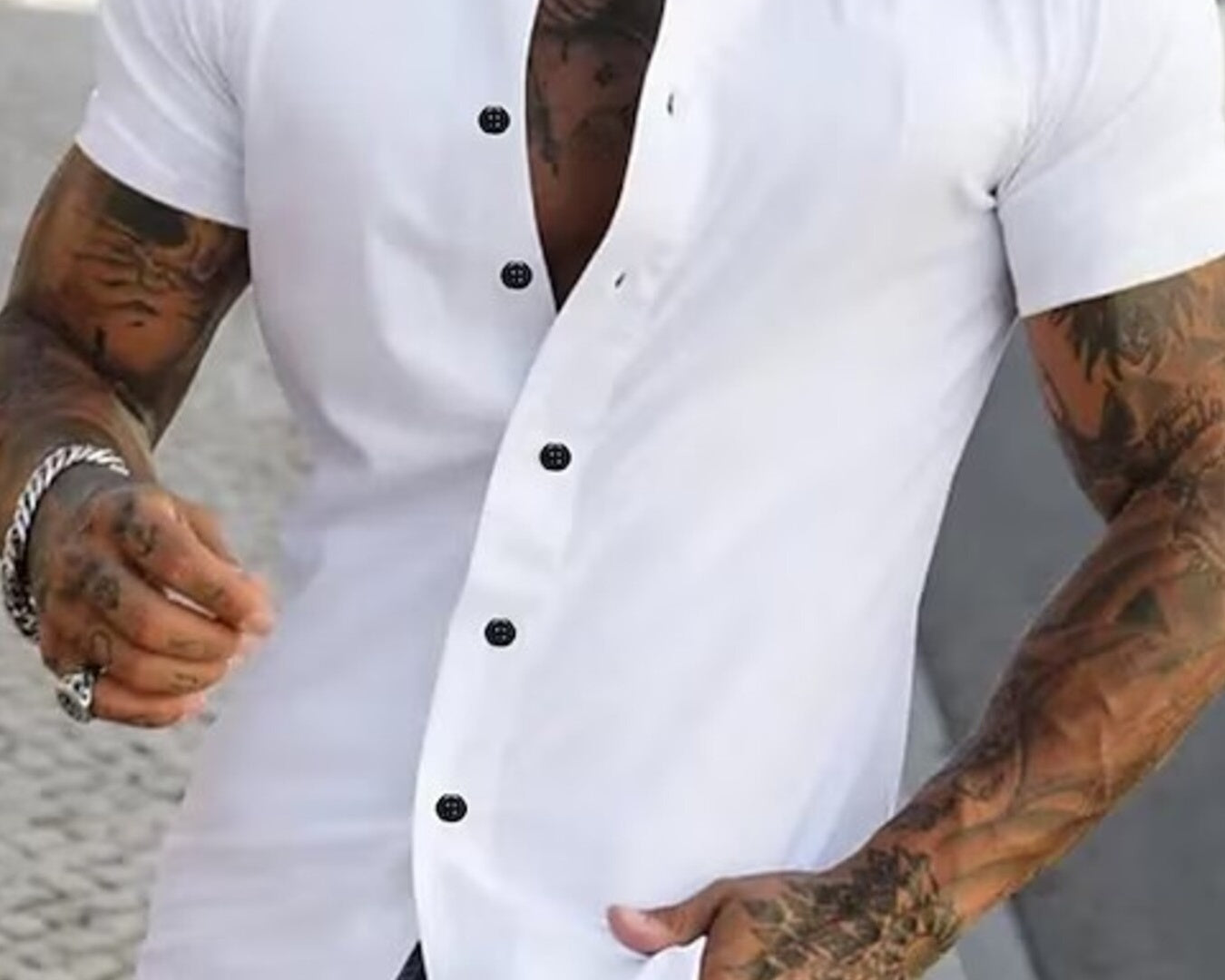 NEWYORKLISTED ATLAS MEN's COLLECTION: Man wearing a white short-sleeve button-up shirt with black buttons, standing outdoors.