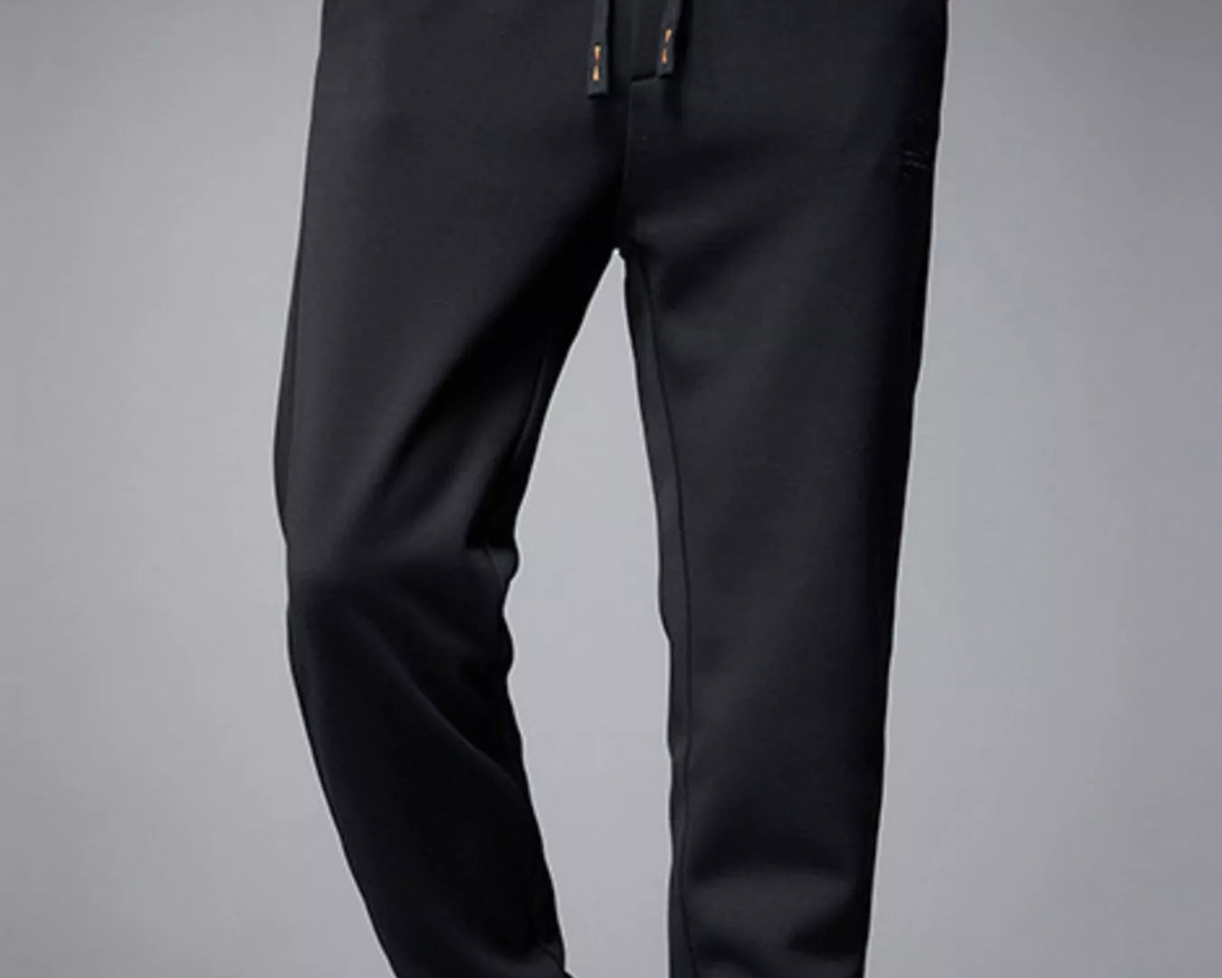 NEWYORKLISTED ATLAS MEN's COLLECTION: Person wearing black jogger pants with green sneakers on a gray background