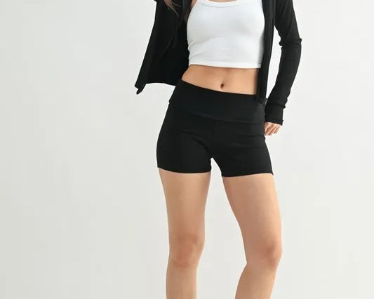 NEWYORKLISTED ACTIVEWEAR: Woman wearing a black jacket, white crop top, and black shorts on a white background