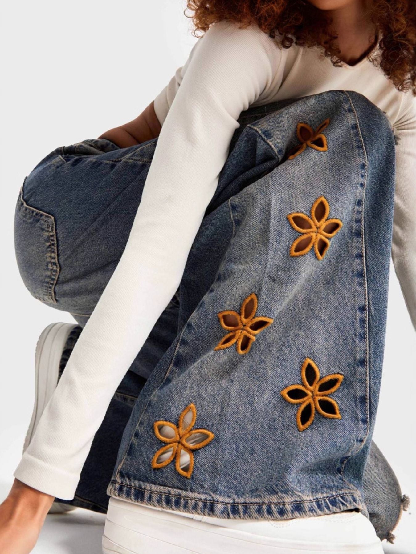 NEWYORKLISTED STYLE COLLECTION: Person wearing a denim jacket with floral embellishments on a white background
