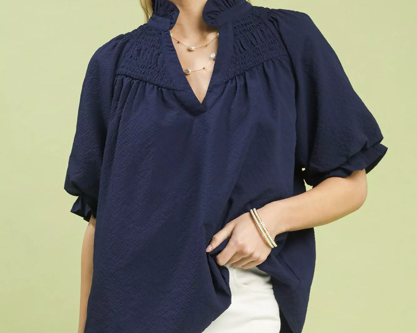 NEWYORKLISTED STYLE COLLECTION: Woman wearing a navy blouse with a green background