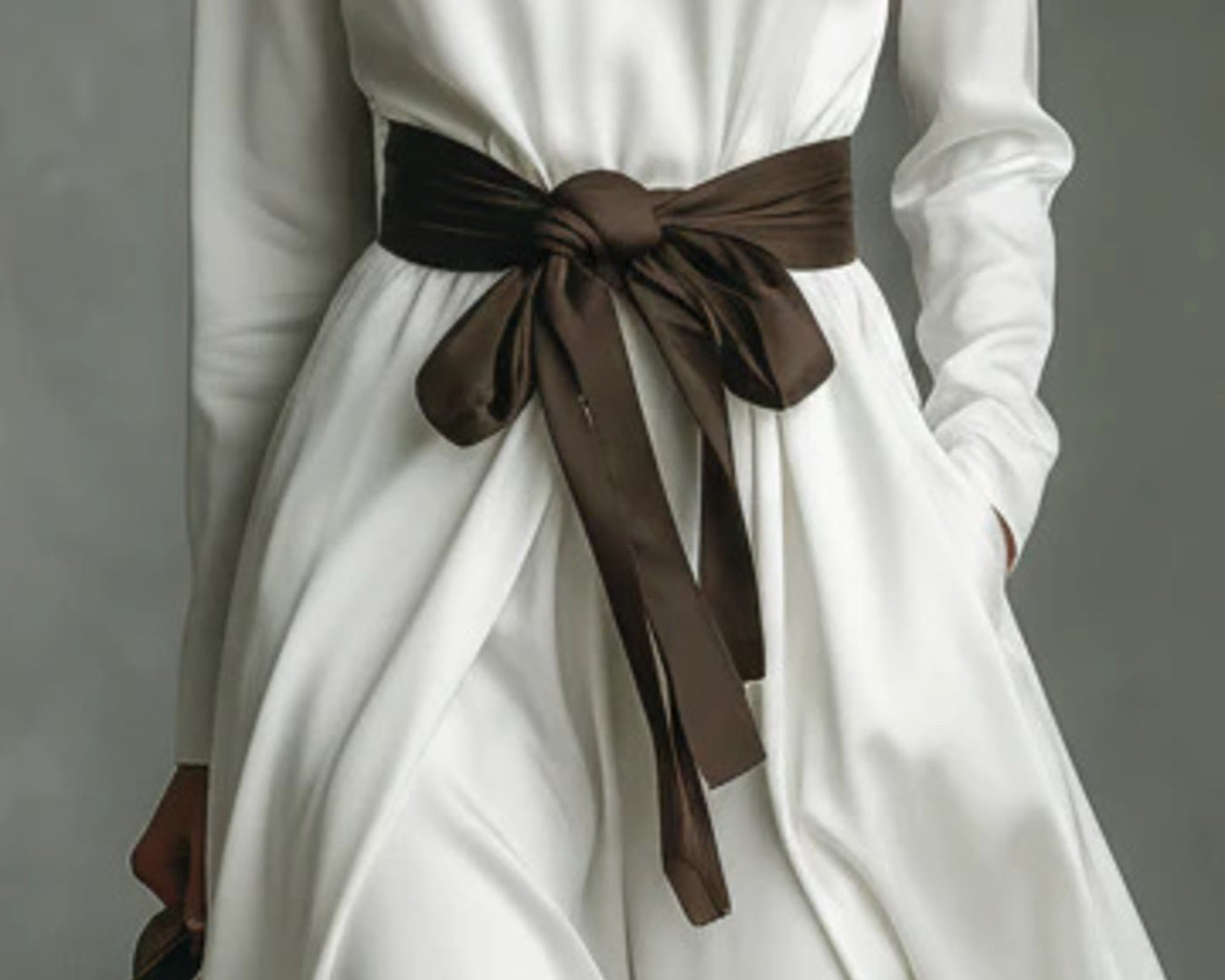 NEWYORKLISTED STYLE COLLECTION: White dress with a brown belt against a gray background