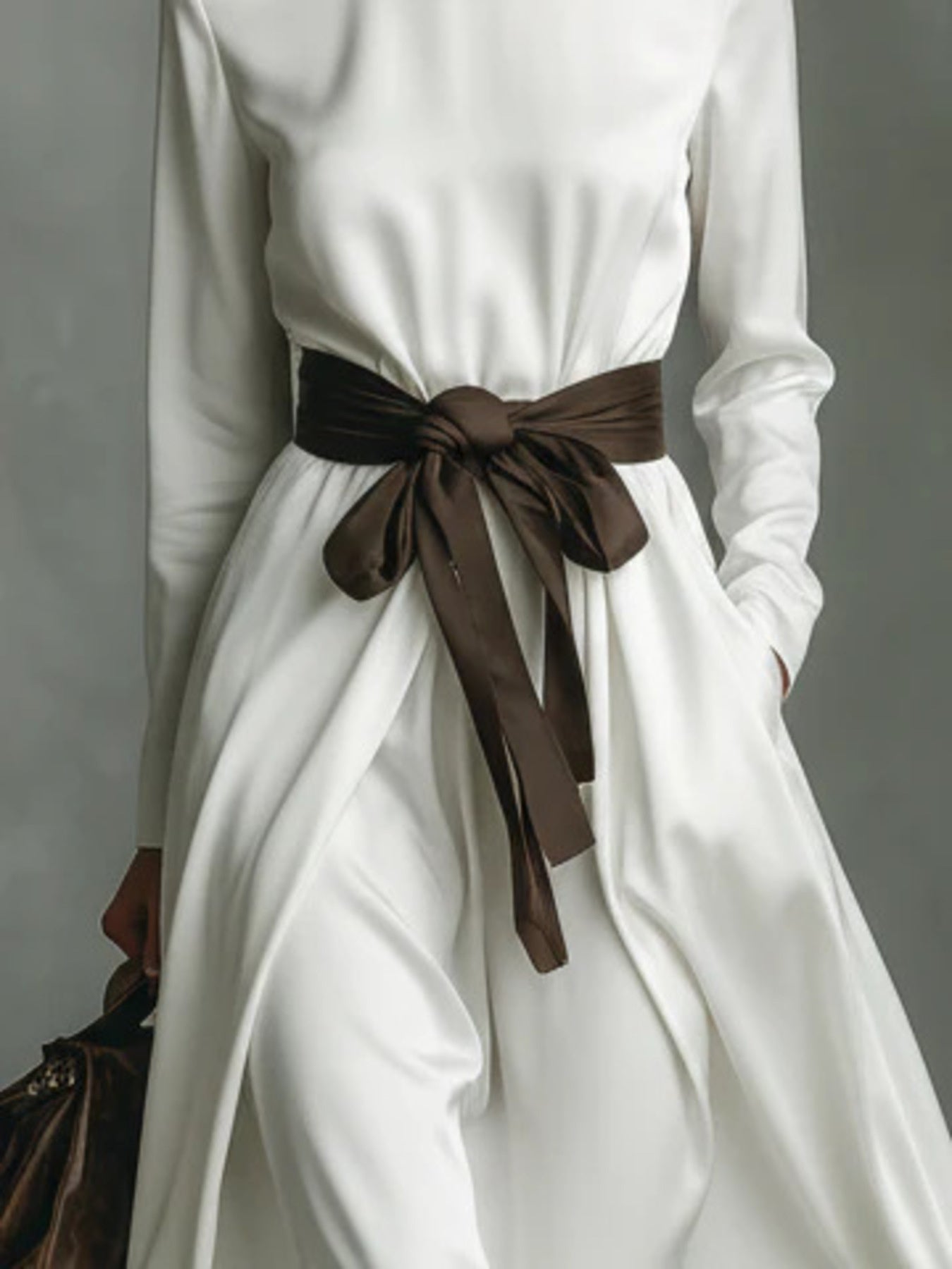 NEWYORKLISTED STYLE COLLECTION: White dress with a brown belt against a gray background