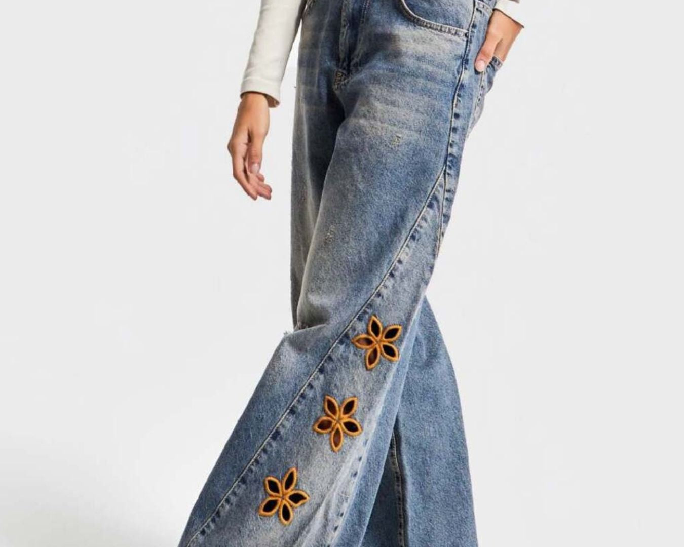 NEWYORKLISTED STYLE COLLECTION: Blue jeans with floral embellishments on a white background