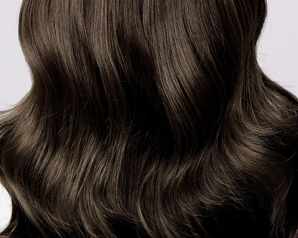 NEWYORKLISTED COSMETIC COLLECTION: Grow Hair Oil, Close-up of long, dark brown hair on a light gray background
