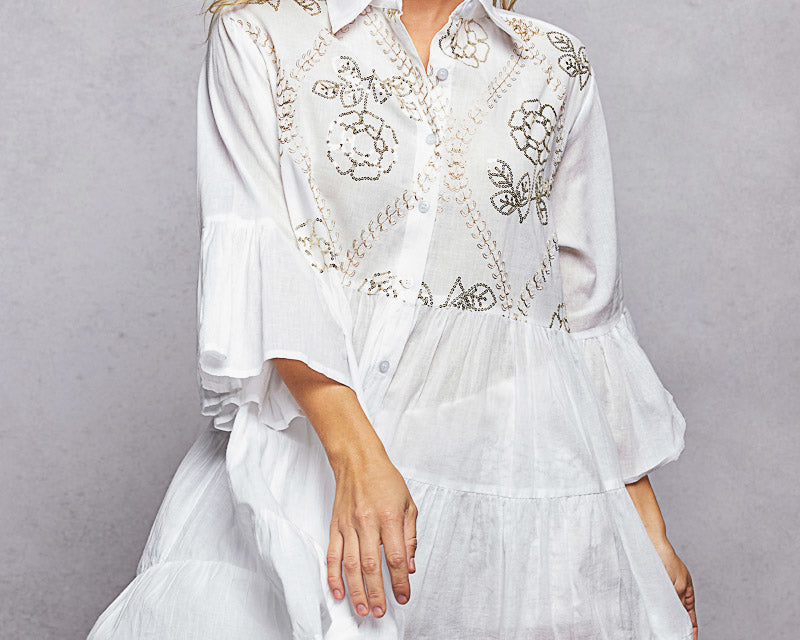 NEWYORKLISTED STYLE COLLECTION: Woman wearing a white embroidered dress against a gray background