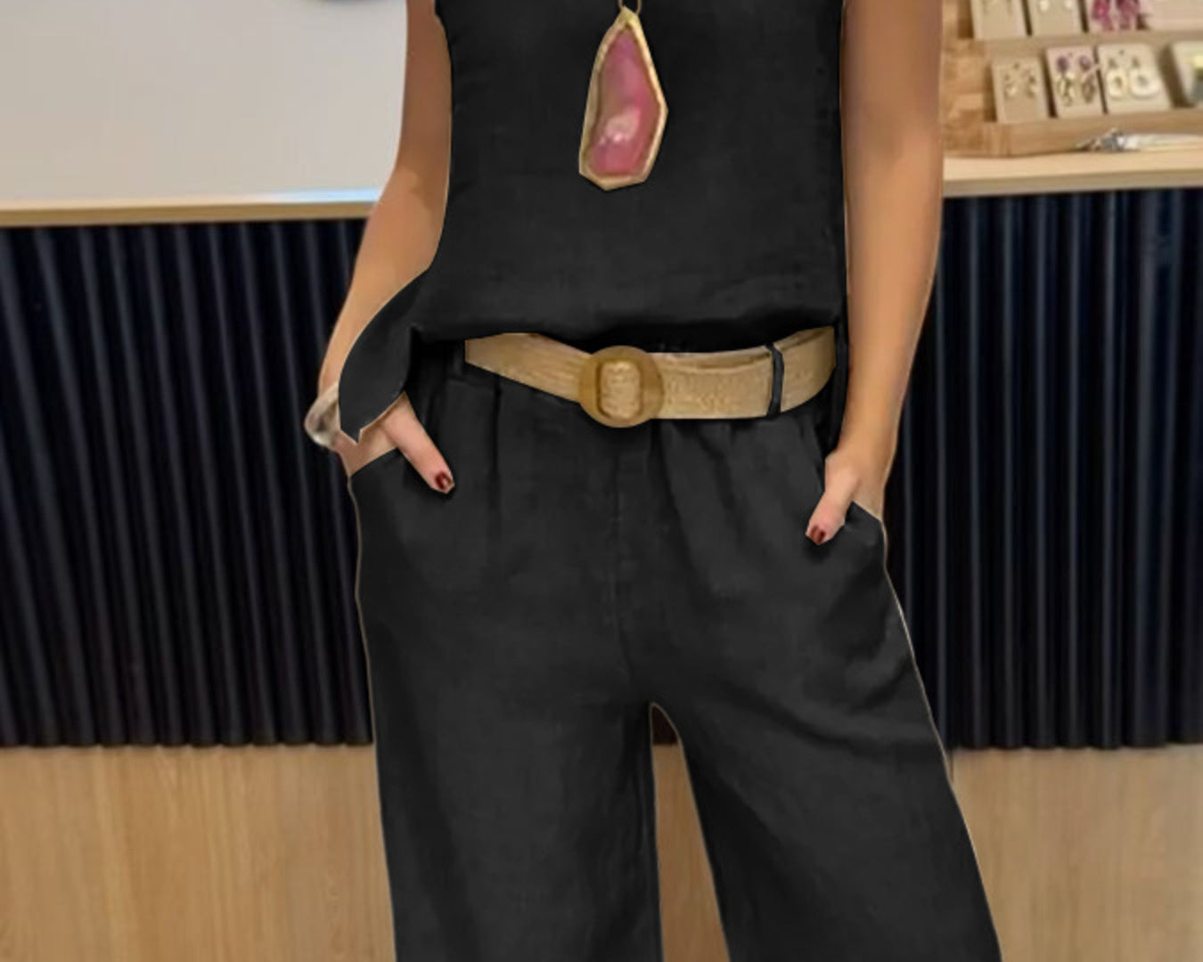 NEWYORKLISTED COMFORT COLLECTION: Person wearing a black sleeveless top and wide-leg pants with a belt, standing indoors.