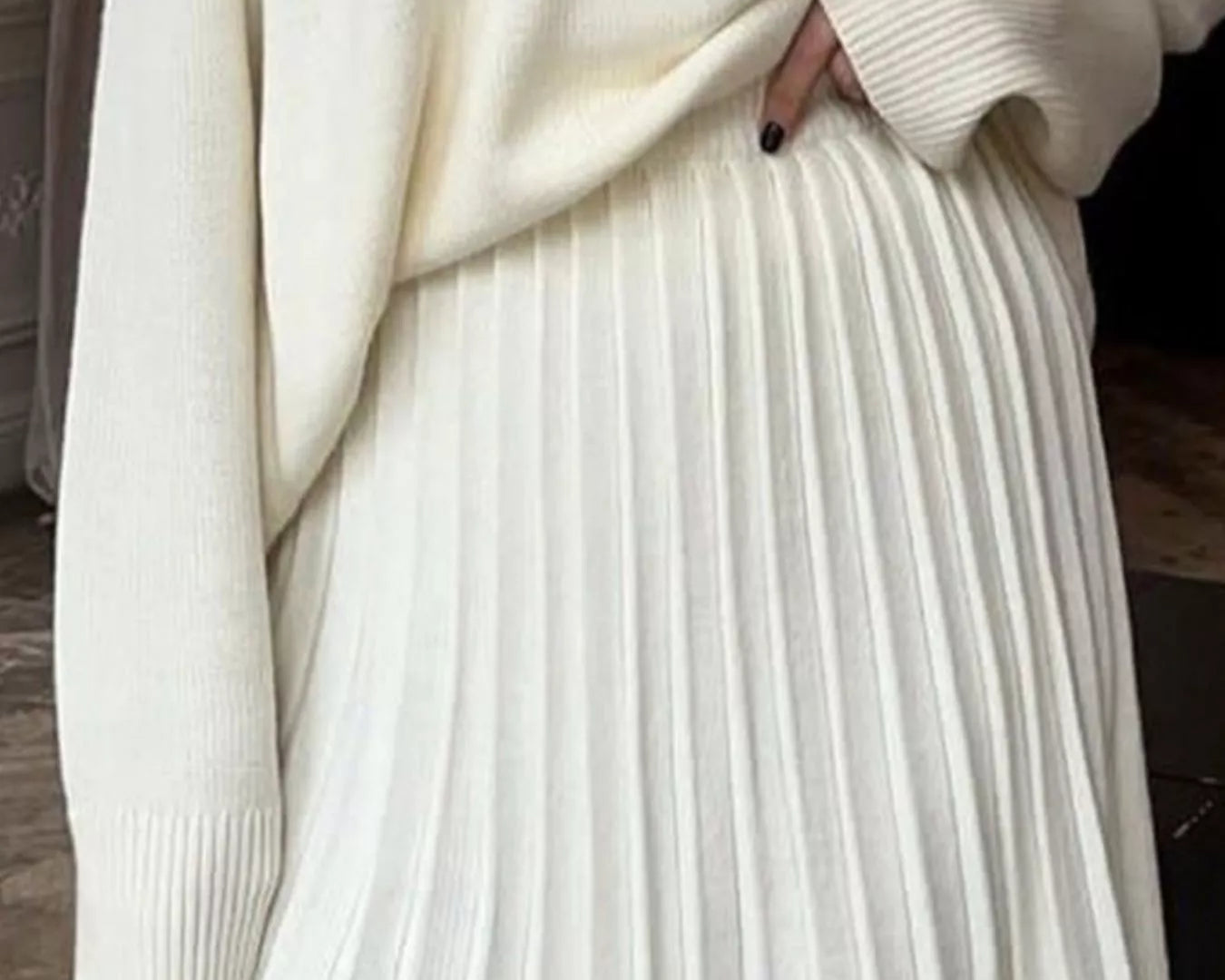 NEWYORKLISTED STYLE COLLECTION: Person wearing a cream sweater and pleated white skirt.