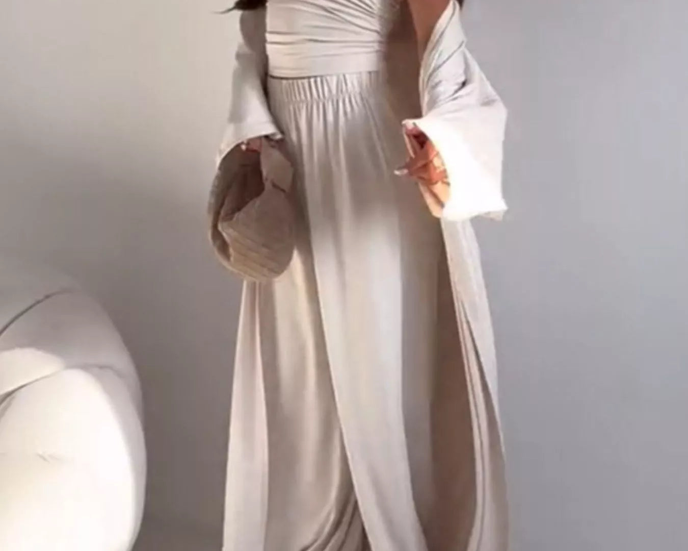 NEWYORKLISTED COMFORT COLLECTION: Woman wearing a white strapless dress with long sleeves against a plain background