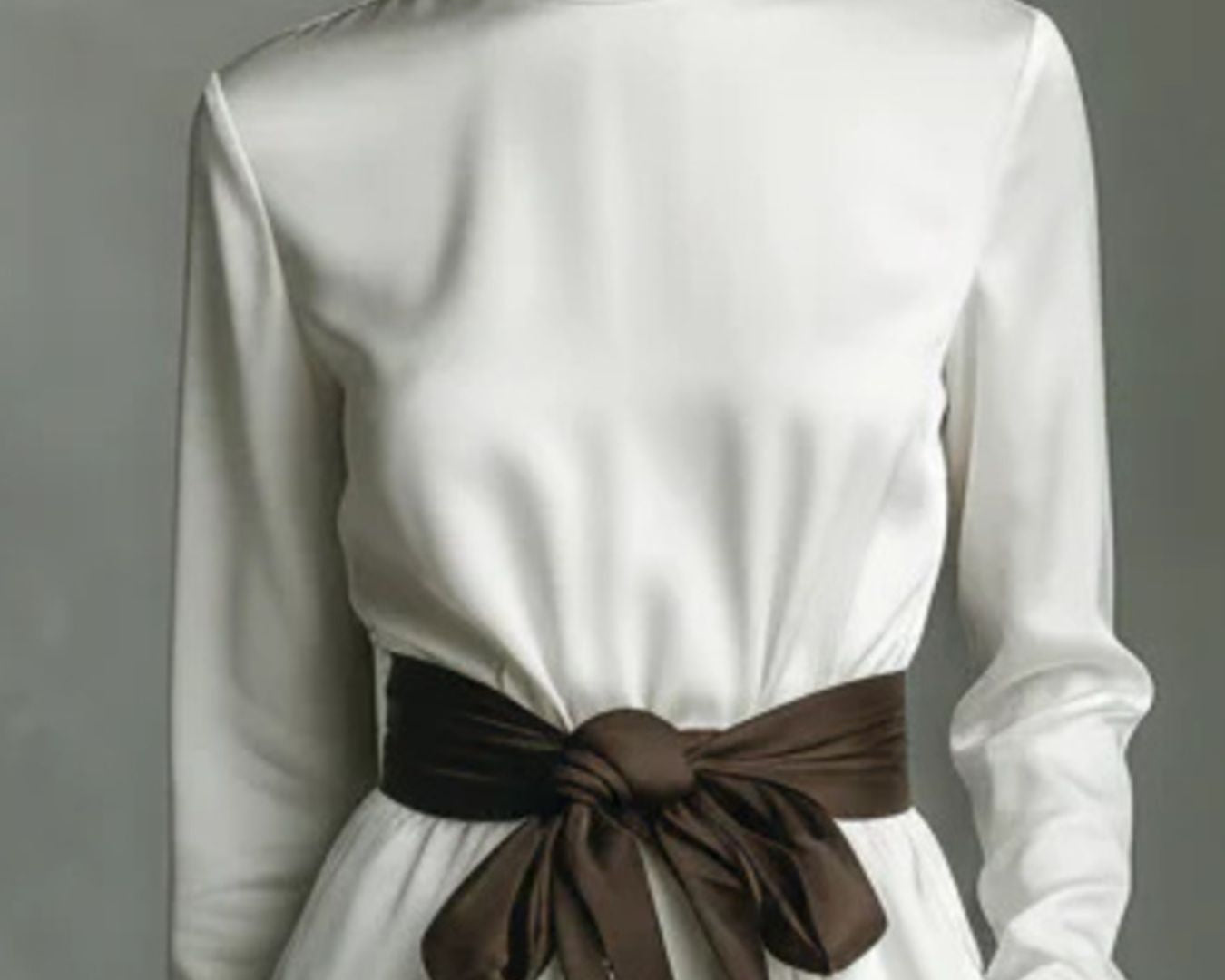 NEWYORKLISTED STYLE COLLECTION: White turtleneck dress with a brown belt against a gray background