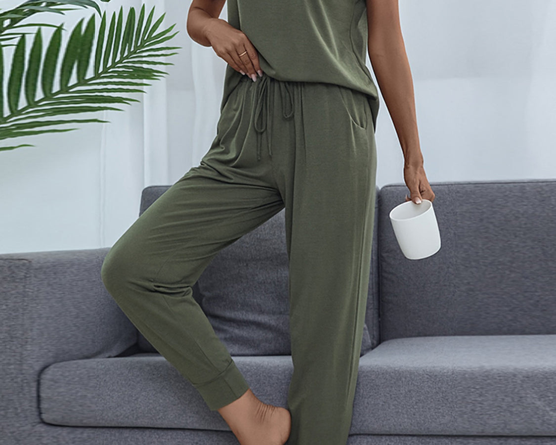 NEWYORKLISTED Intimate Apparel: Person wearing an olive green outfit sitting on a gray sofa with a plant in the background