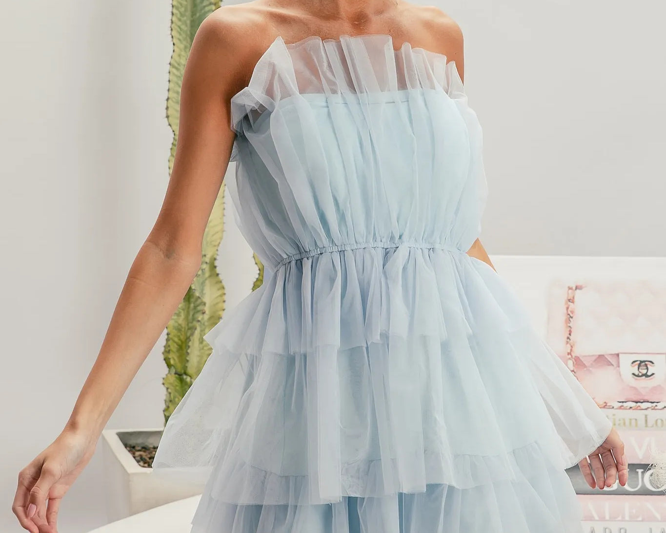 Woman wearing a light blue strapless dress with a blurred indoor background