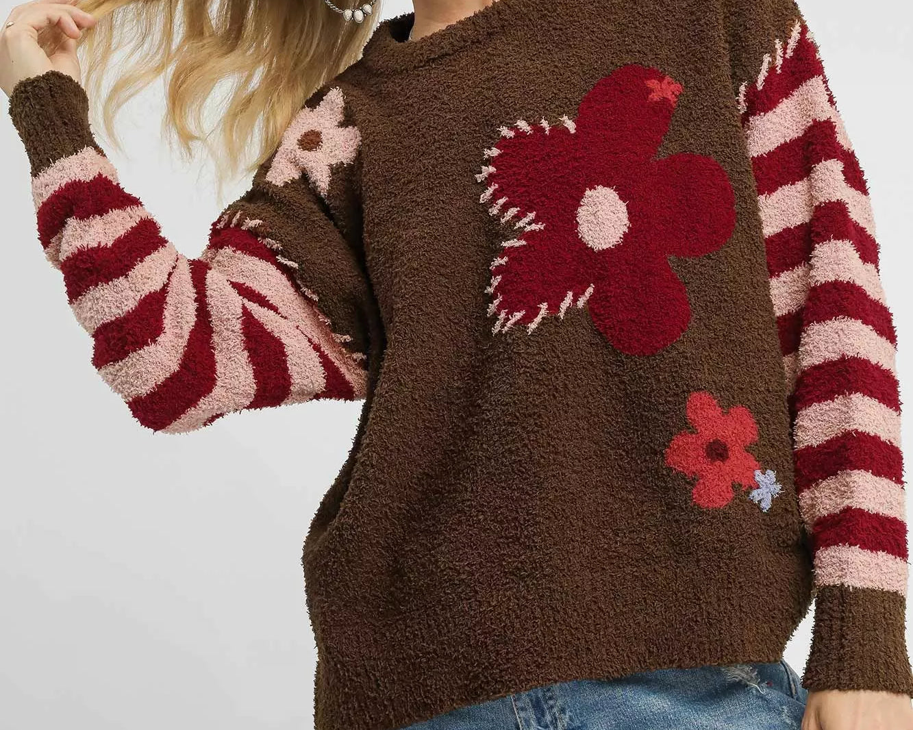 NEWYORKLISTED STYLE COLLECTION: Woman wearing a brown sweater with floral patterns and striped sleeves on a white background