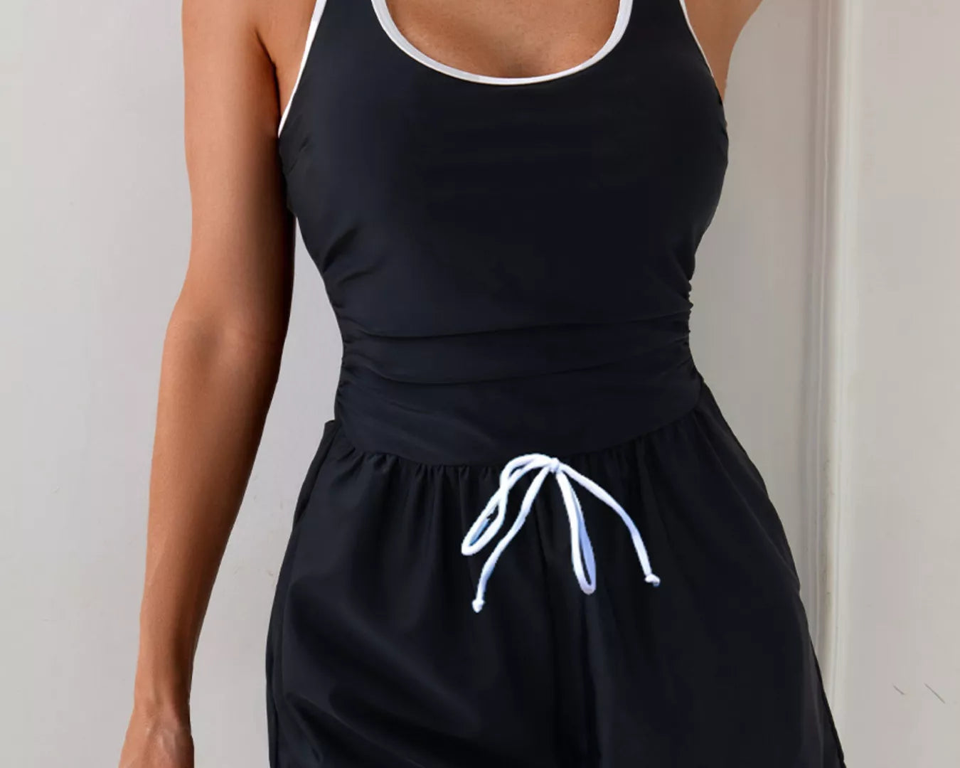 NEWYORKLISTED STYLE COLLECTION: Woman wearing a black tank top and shorts set with white drawstring against a light background