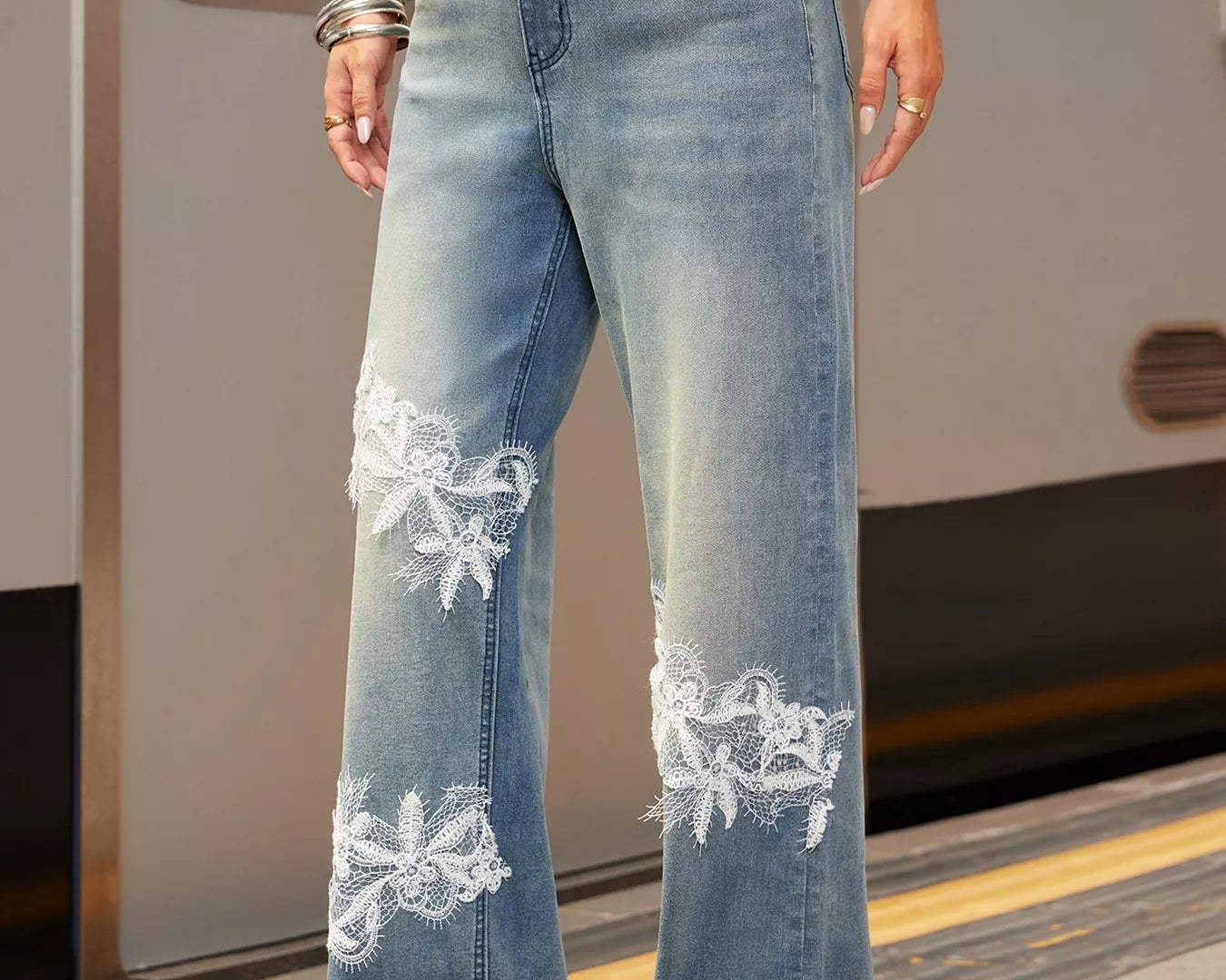 NEWYORKLISTED STYLE COLLECTION: Person wearing light blue jeans with floral embroidery on a train platform.