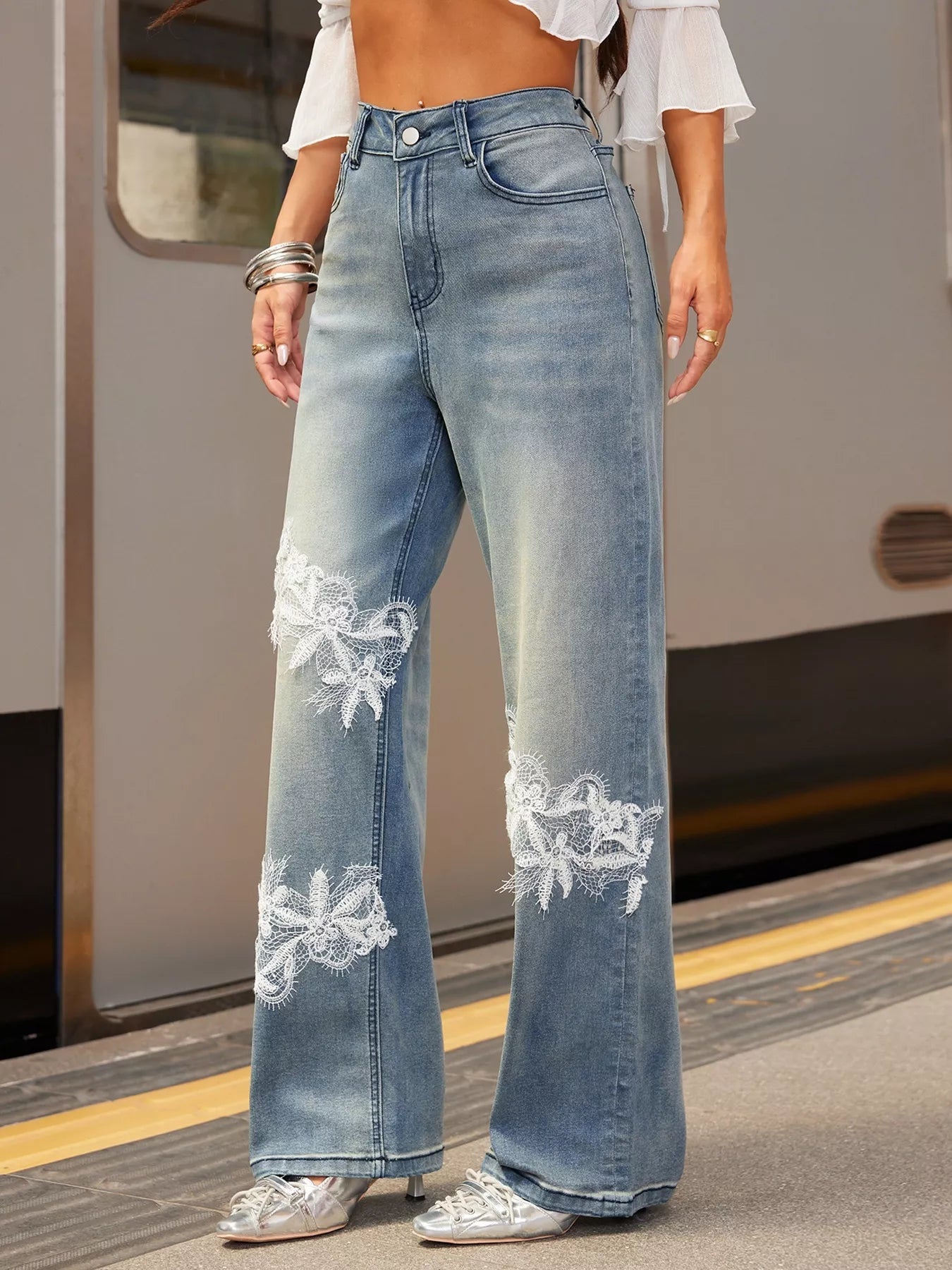 NEWYORKLISTED STYLE COLLECTION: Person wearing light blue jeans with floral embroidery on a train platform.