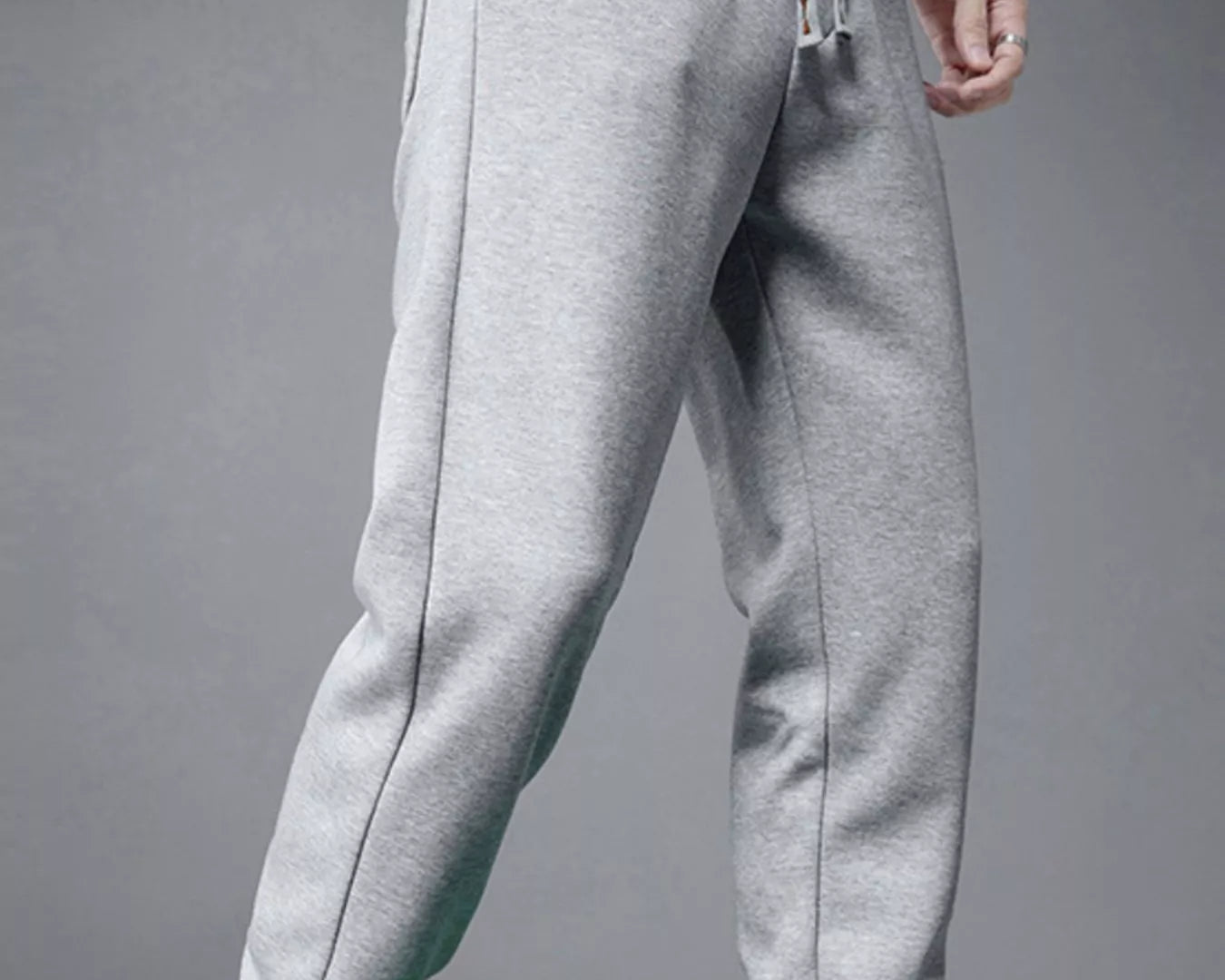 NEWYORKLISTED ATLAS MEN's COLLECTION: Gray sweatpants worn with a white top and green shoes on a gray background