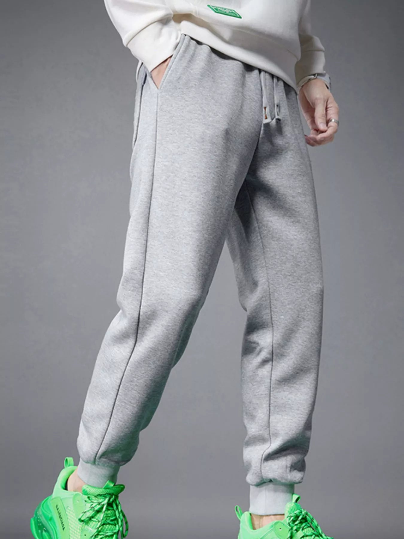NEWYORKLISTED ATLAS MEN's COLLECTION: Gray sweatpants worn with a white top and green shoes on a gray background