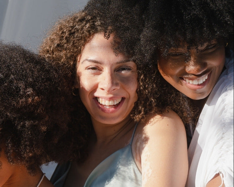 NEWYORKLISTED Cosmetic Collection: Natural Curl Care products, three women smiling on a pink background