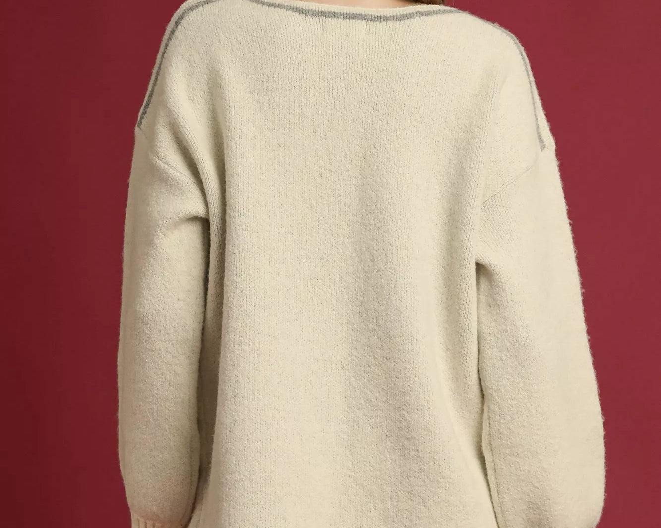 NEWYORKLISTED STYLE COLLECTION: Woman wearing a cream sweater and black cap on a red background