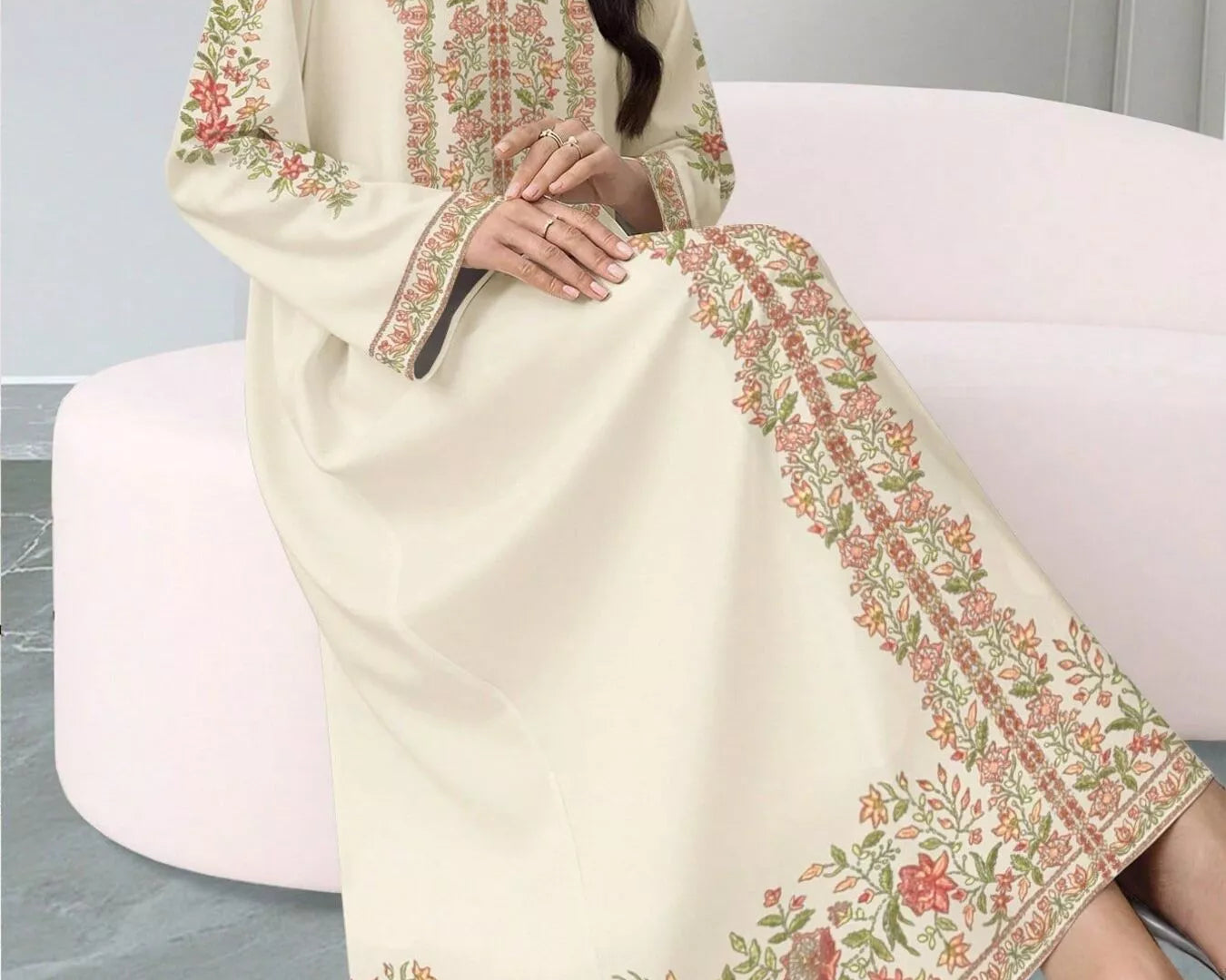 NEWYORKLISTED STYLE COLLECTION: Woman wearing a cream-colored embroidered dress sitting on a white chair.