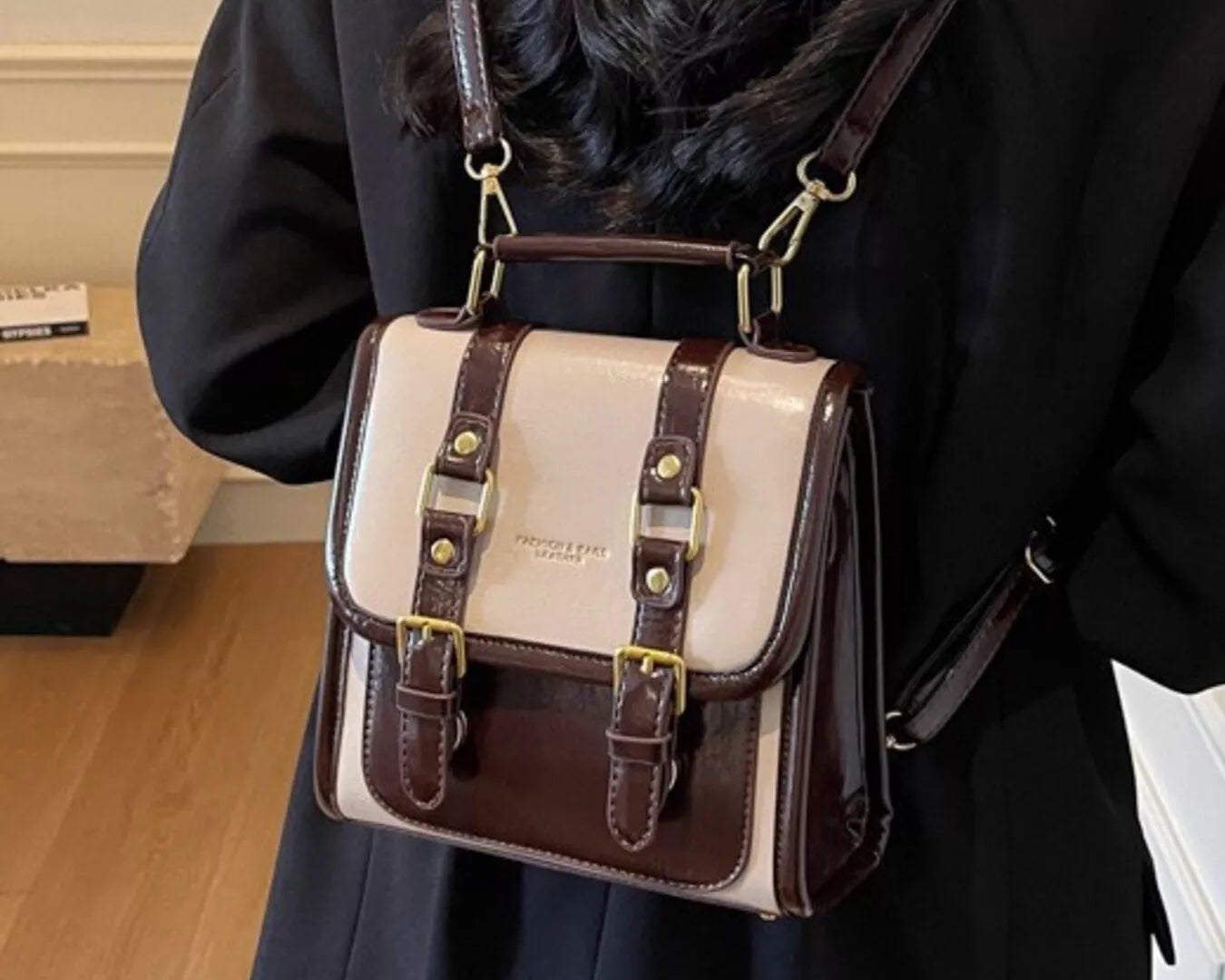 NEWYORKLISTED STYLE COLLECTION: Person wearing a white and brown leather bag over their shoulder indoors.