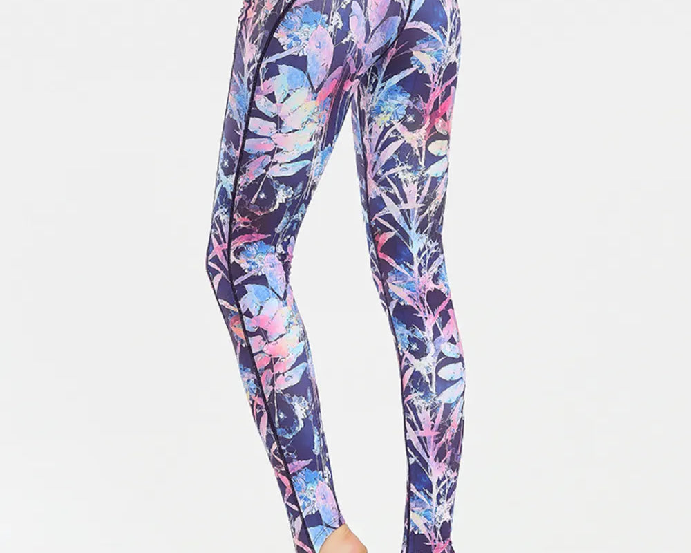 NEWYORKLISTED ACTIVEWEAR COLLECTION: Multicolored leaf-patterned leggings worn by a person on a white background