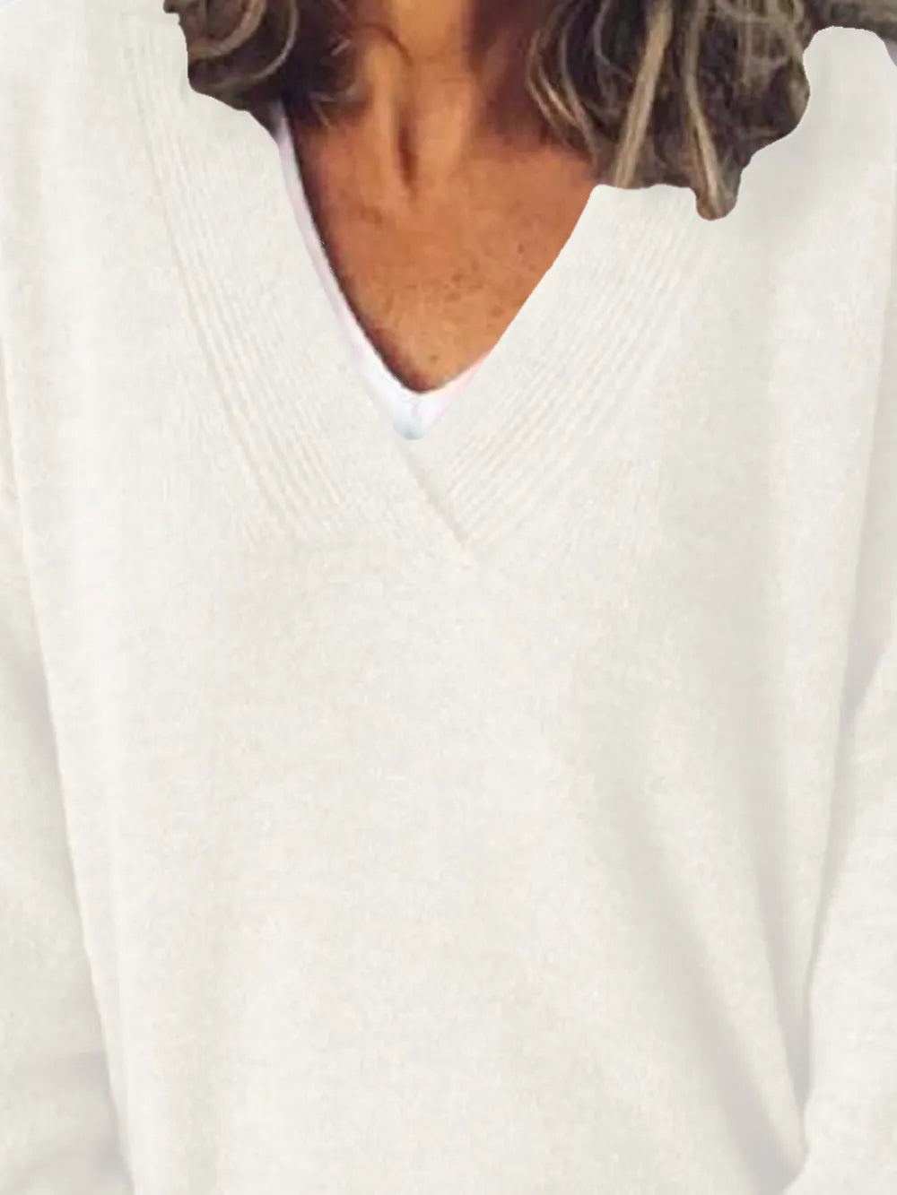 NEWYORKLISTED STYLE COLLECTION: Close-up of a person wearing a white sweater with a V-neck