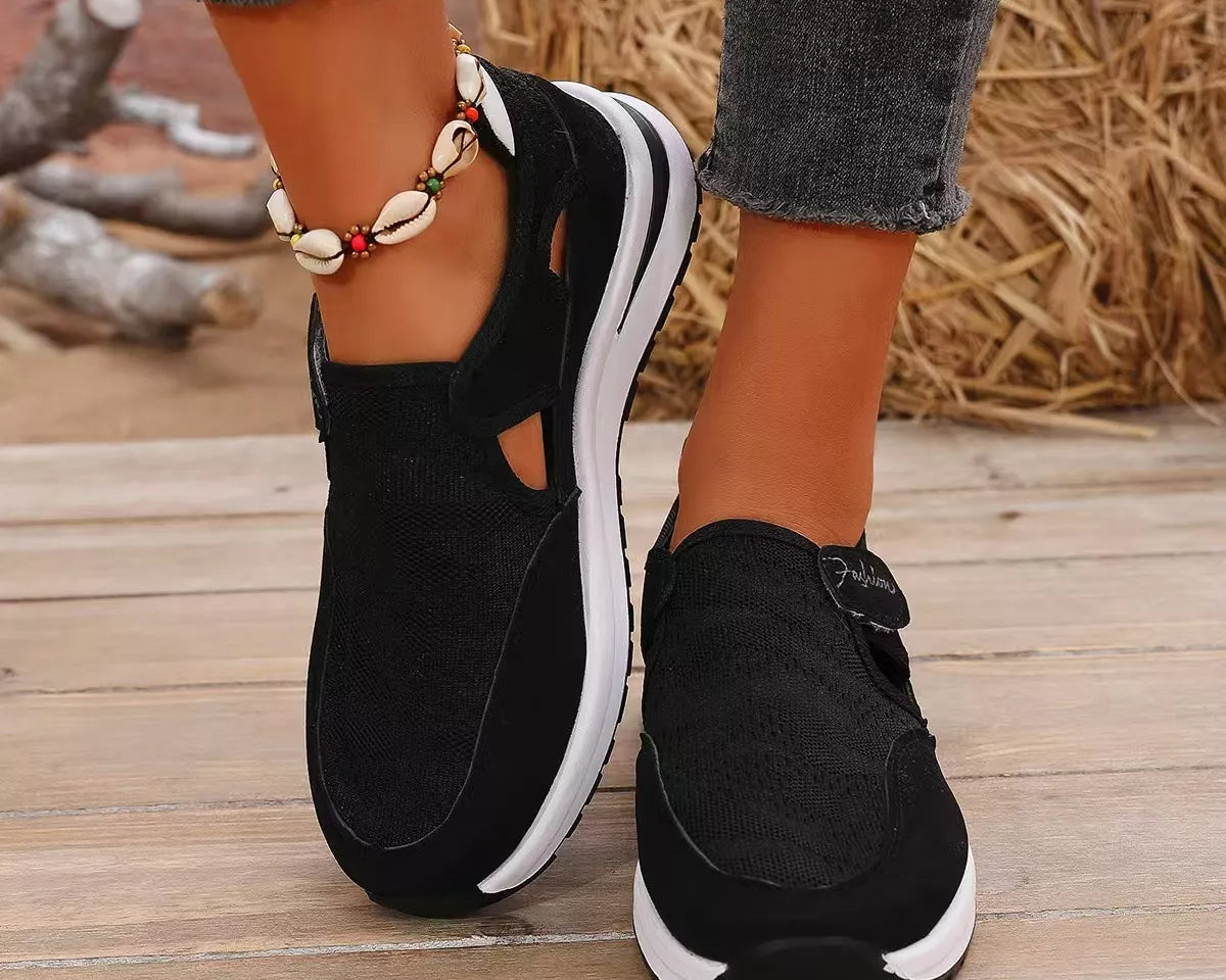 NEWYORKLISTED SHOE COLLECTION: Black sneakers with white soles worn on a wooden floor.