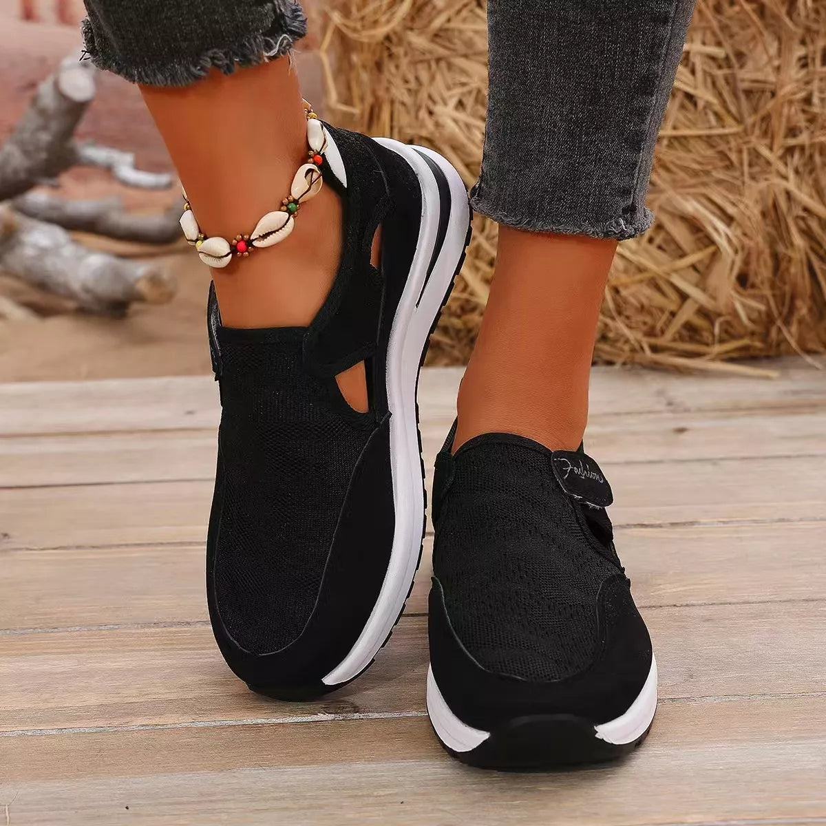 NEWYORKLISTED SHOE COLLECTION: Black sneakers with white soles worn on a wooden floor.