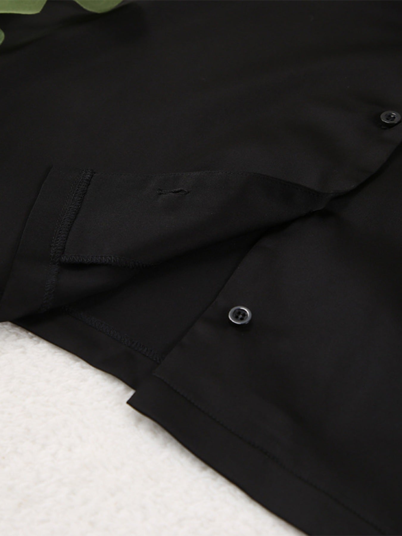 NEWYORKLISTED Intimate Apparel Collection: Close-up of a black jacket with a button on a white background