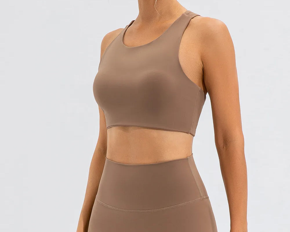 NEWYORKLISTED ACTIVEWEAR COLLECTION: Woman wearing a brown sports bra and leggings on a light gray background