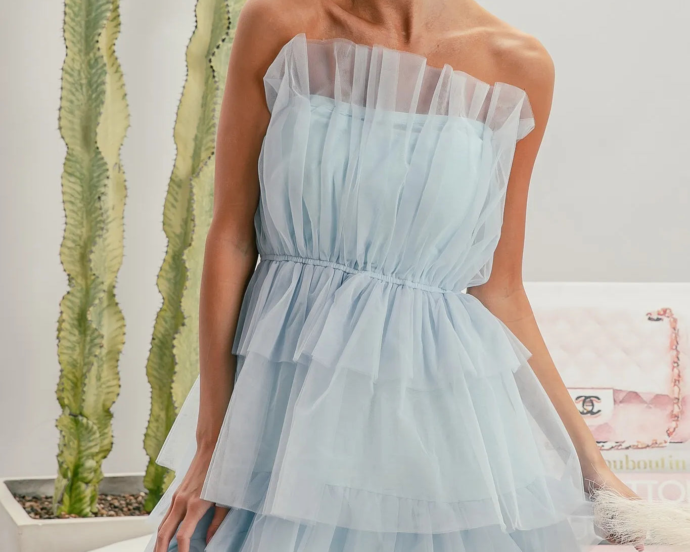 Woman wearing a light blue strapless dress with sunglasses indoors.