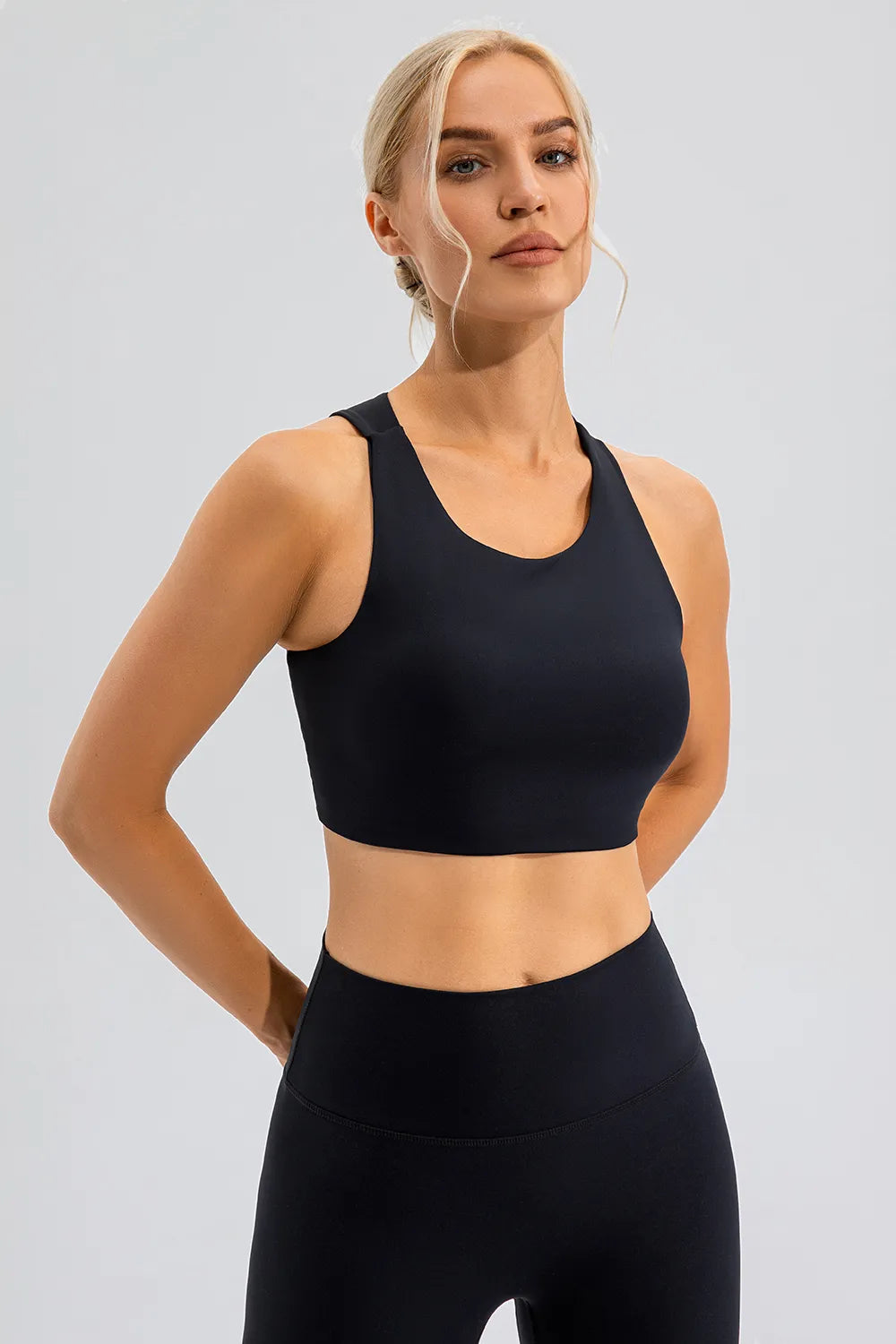 NEWYORKLISTED ACTIVEWEAR COLLECTION: Woman wearing a black sports bra and leggings on a light gray background