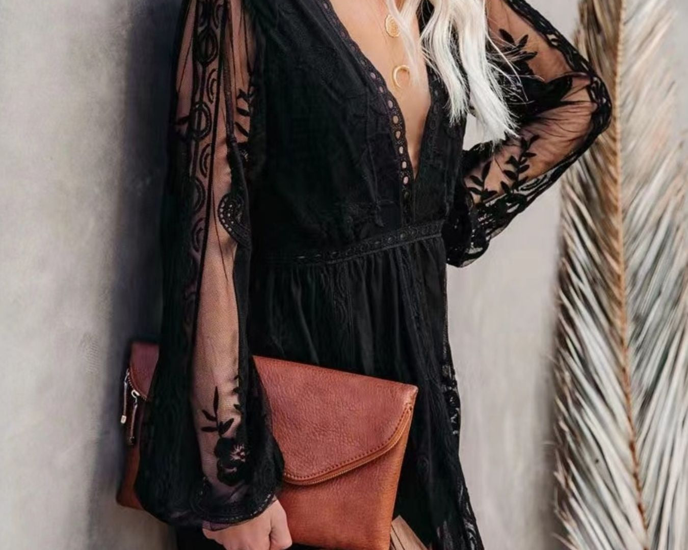 NEWYORKLISTED STYLE COLLECTION: Woman wearing a black lace dress with sheer sleeves against a neutral background