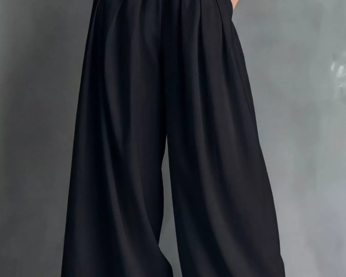 NEWYORKLISTED STYLE COLLECTION: Person wearing a white top and black wide-leg pants with a belt on a gray background