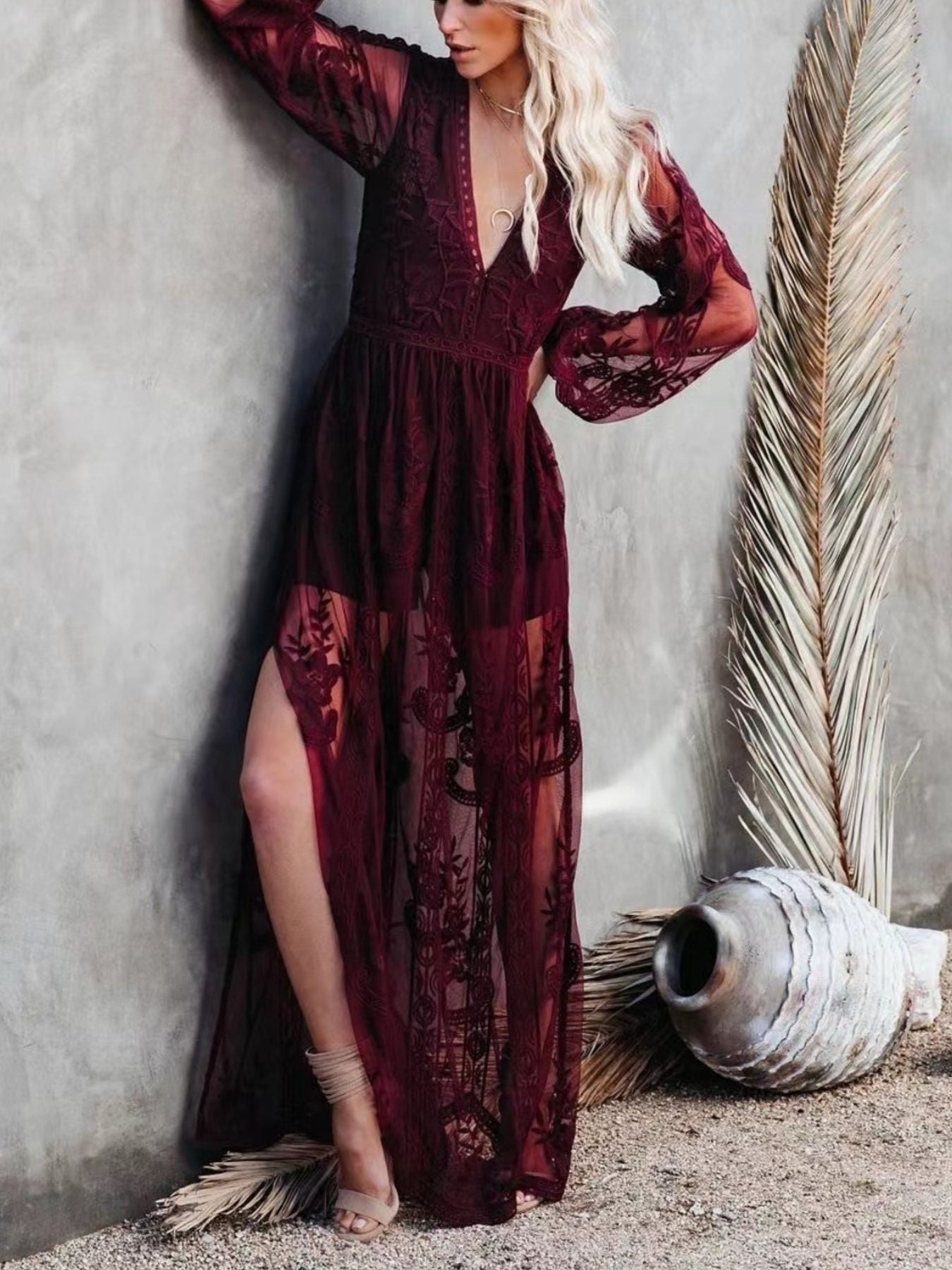 NEWYORKLISTED STYLE COLLECTION: Woman wearing a burgundy lace dress against a textured wall.