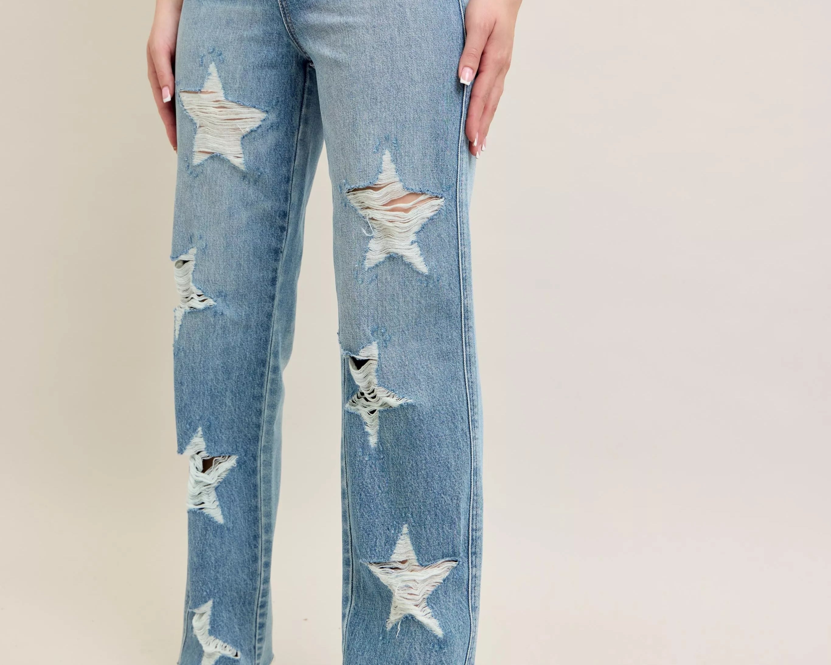 NEWYORKLISTED STYLE COLLECTION: Blue jeans with star patterns worn by a person on a plain background