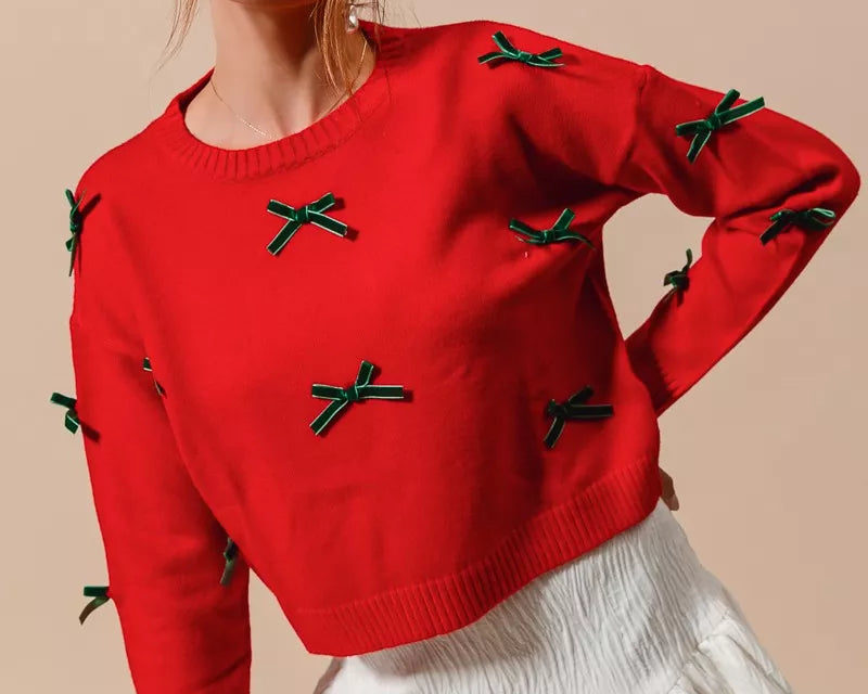 NEWYORKLISTED STYLE COLLECTION: Woman wearing a red sweater with green bows and a white skirt on a beige background