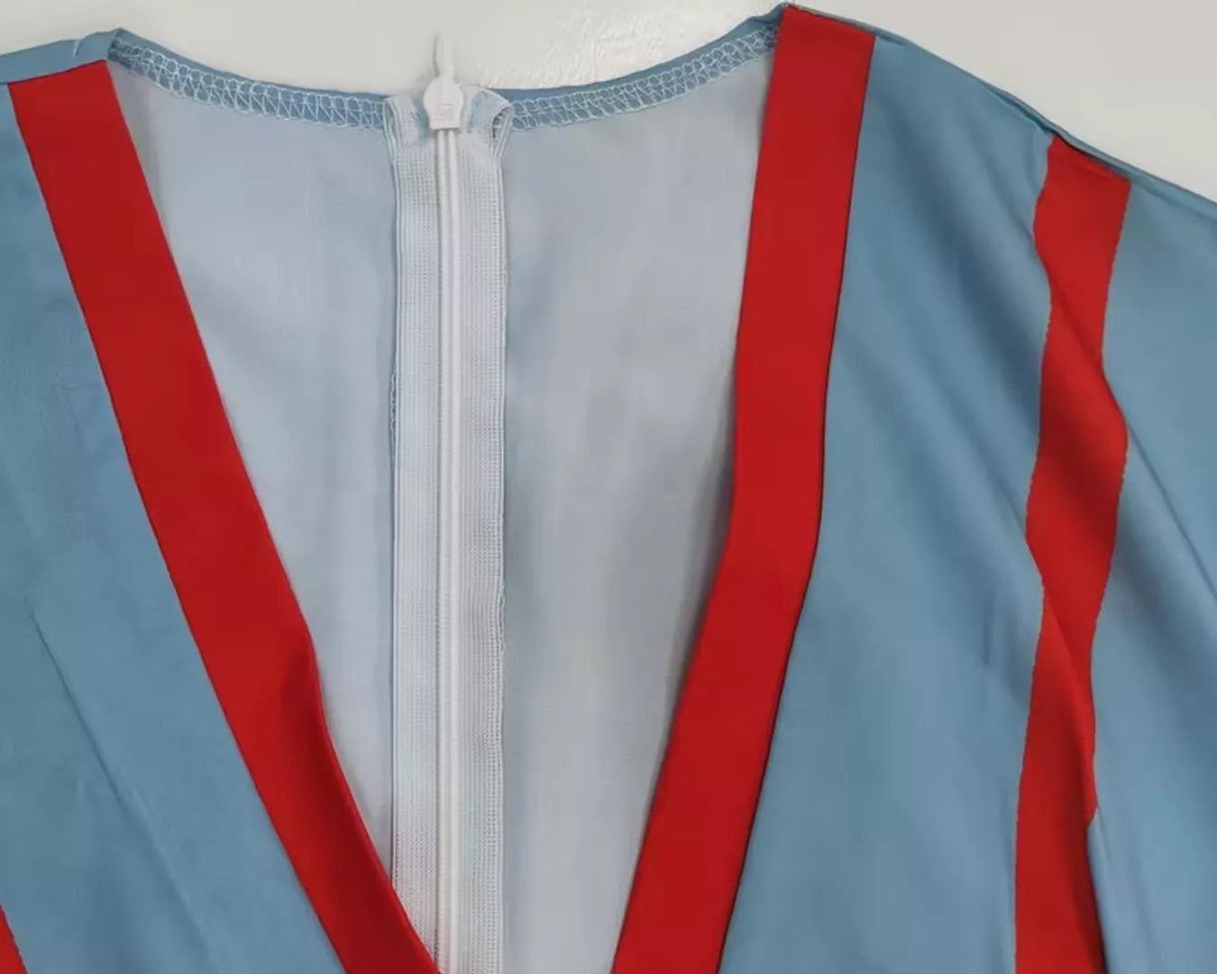 NEWYORKLISTED STYLE COLLECTION: Close-up of a garment with red and blue stripes on a plain background